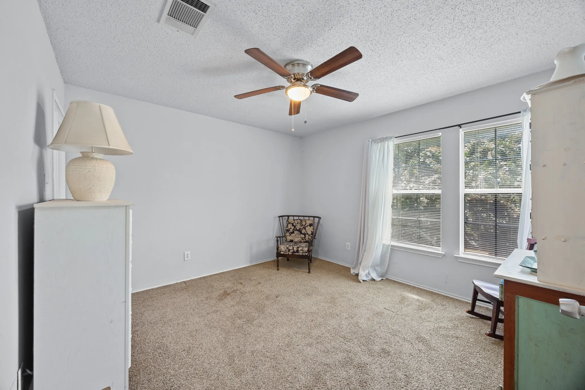 Dual windows with blinds, ceiling fan, and textured ceiling