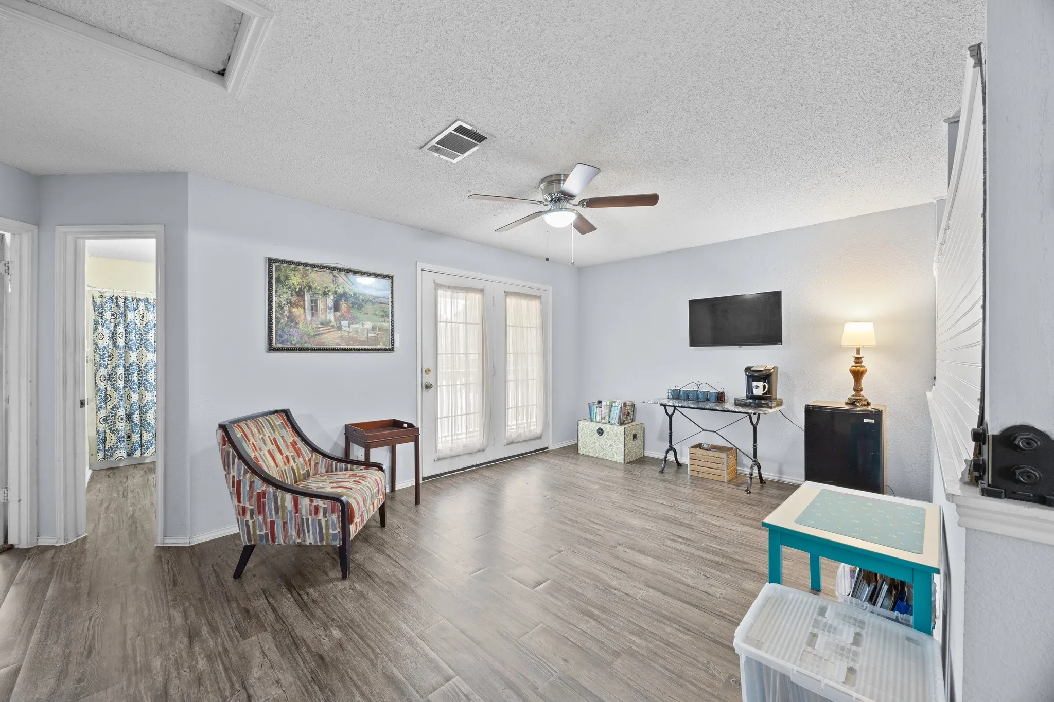 Wood-finish flooring throughout, ceiling fan, and double glass doors
