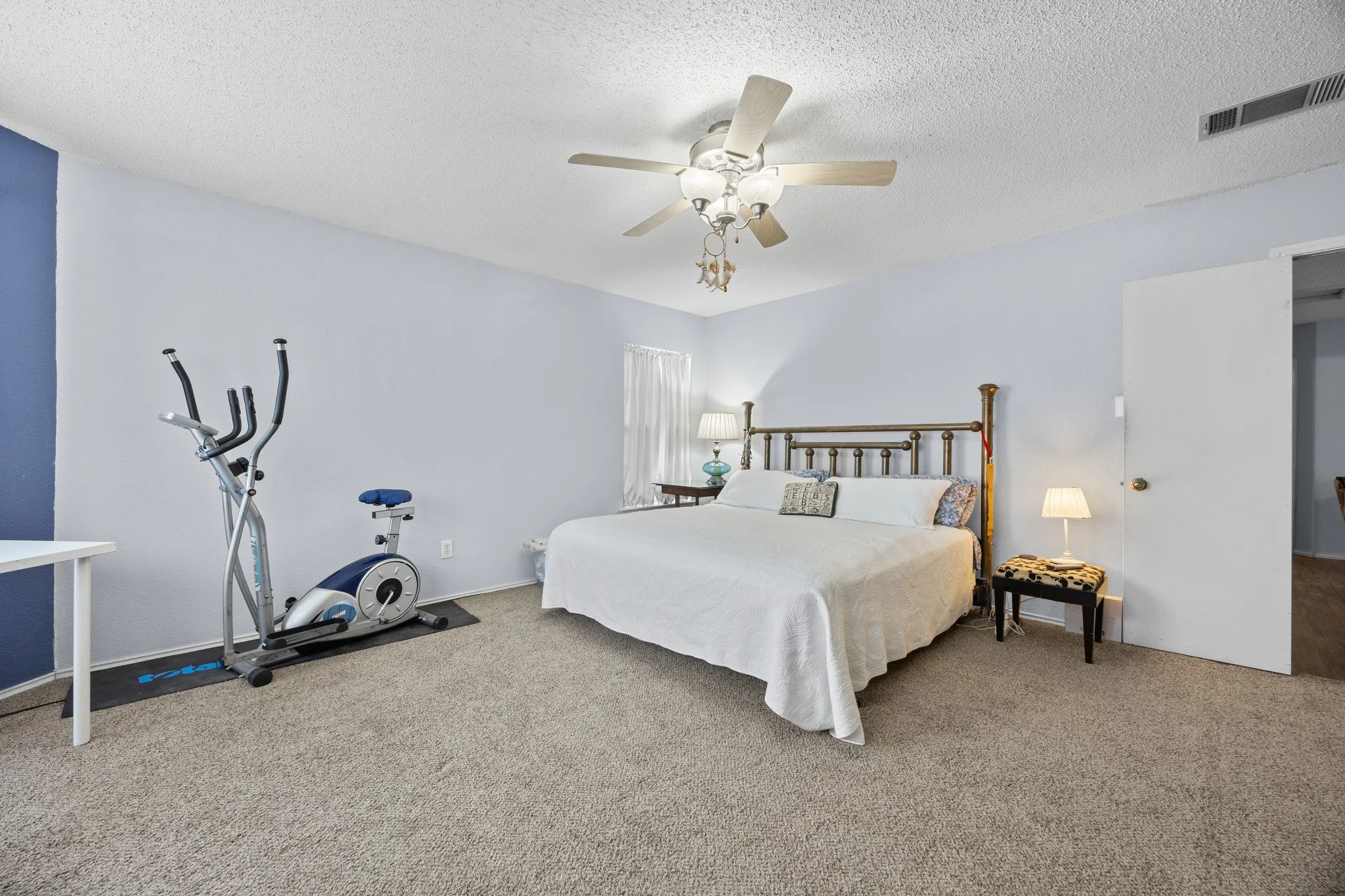 Carpeted room with a ceiling fan, light blue wall paint, and a white door