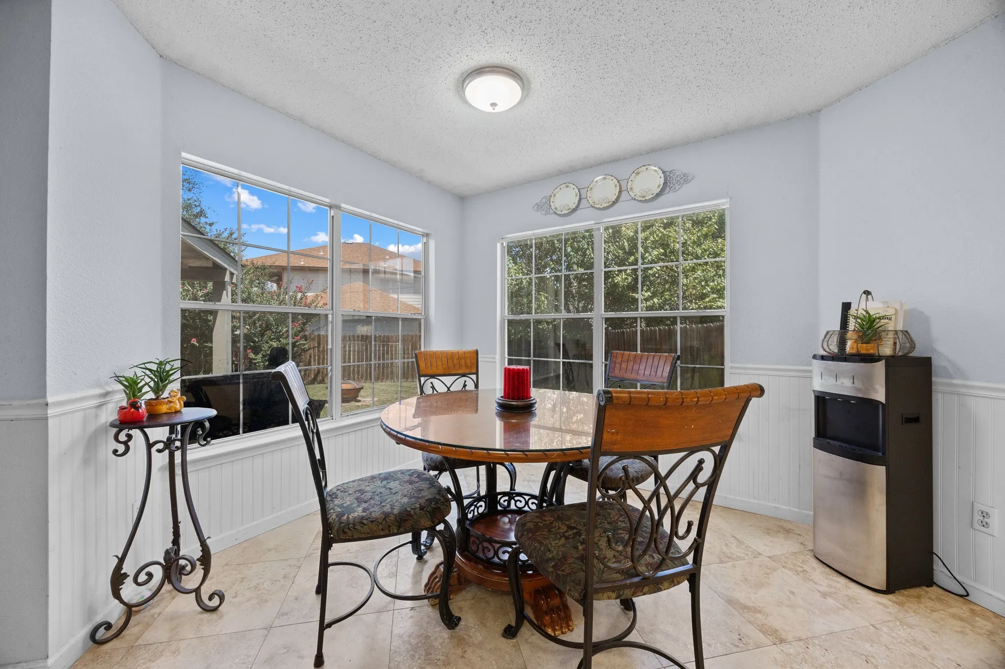 Tile flooring, white wainscoting, light-colored walls, multiple windows, and a ceiling-mounted light fixture