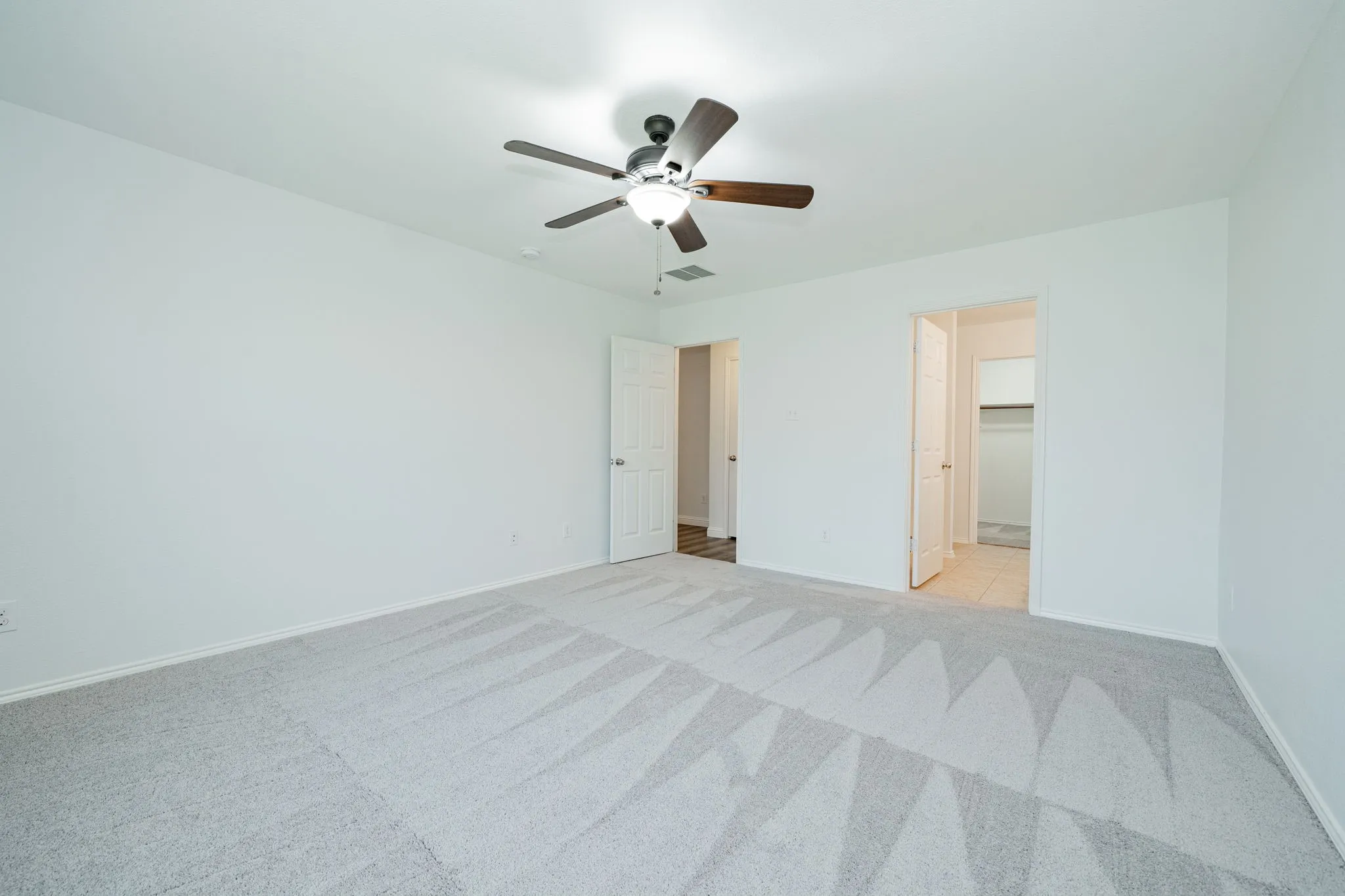 Unfurnished bedroom with light colored carpet and ceiling fan