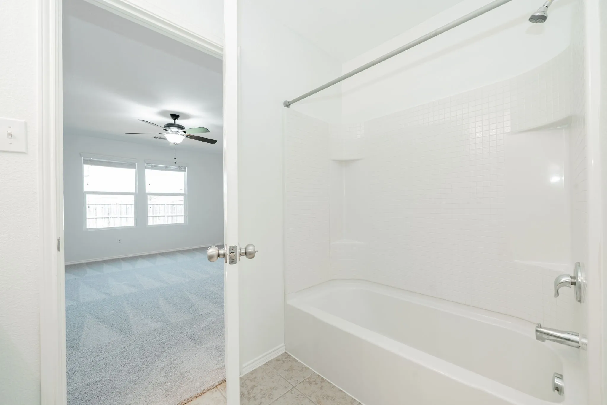 Full bath with bathing tub / shower combination, a ceiling fan, and tile patterned flooring