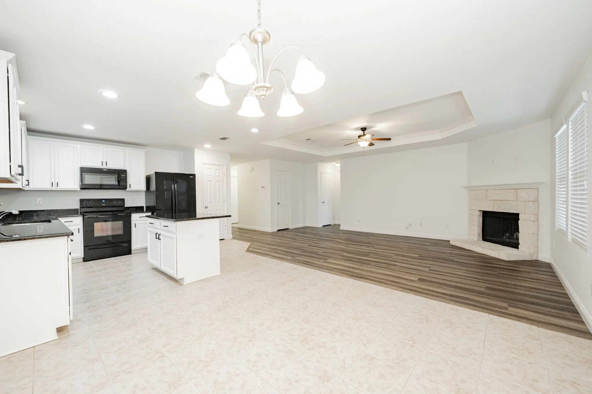 Kitchen with black appliances, dark countertops, ceiling fan, a chandelier, and crown molding