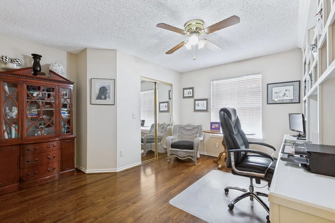 Wood-finish flooring, built-in shelving, ceiling fan, window with blinds, and mirrored closet doors