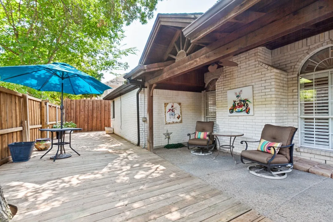 Outdoor deck with wood fencing, brick exterior, arched windows, and a covered patio area