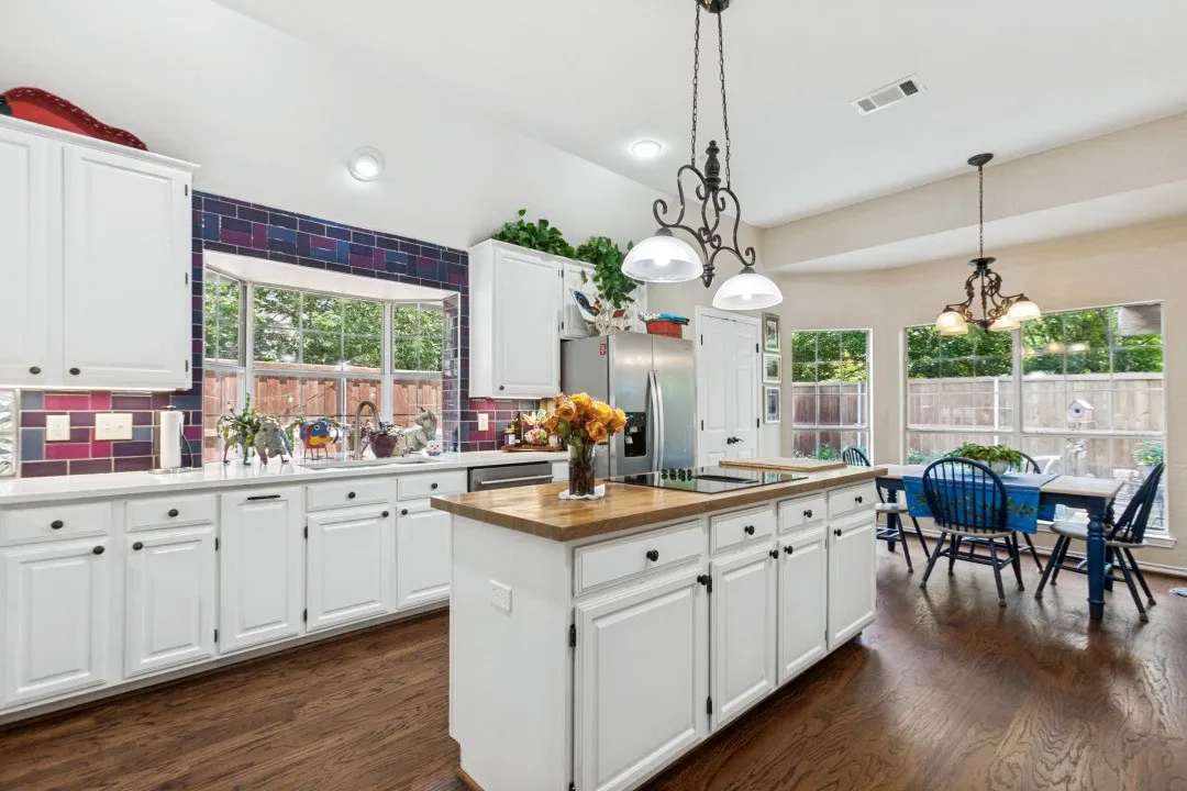 White cabinetry with black hardware, wood-finish flooring, and a central kitchen island