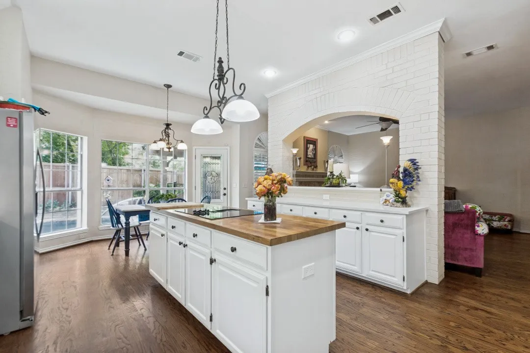 Kitchen island with wood-finish countertop, white cabinetry, dark wood-finish flooring, recessed lighting, and an arched brick-finish partition