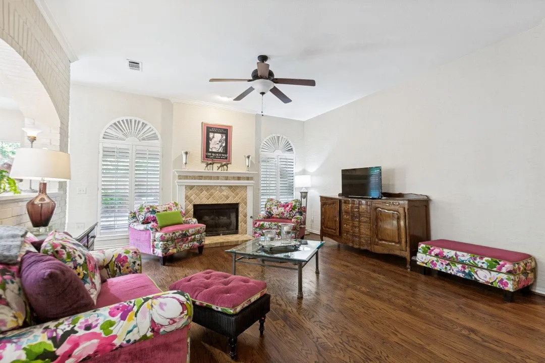 Hardwood flooring, arched windows with plantation shutters, brick archway, recessed lighting, and a ceiling fan