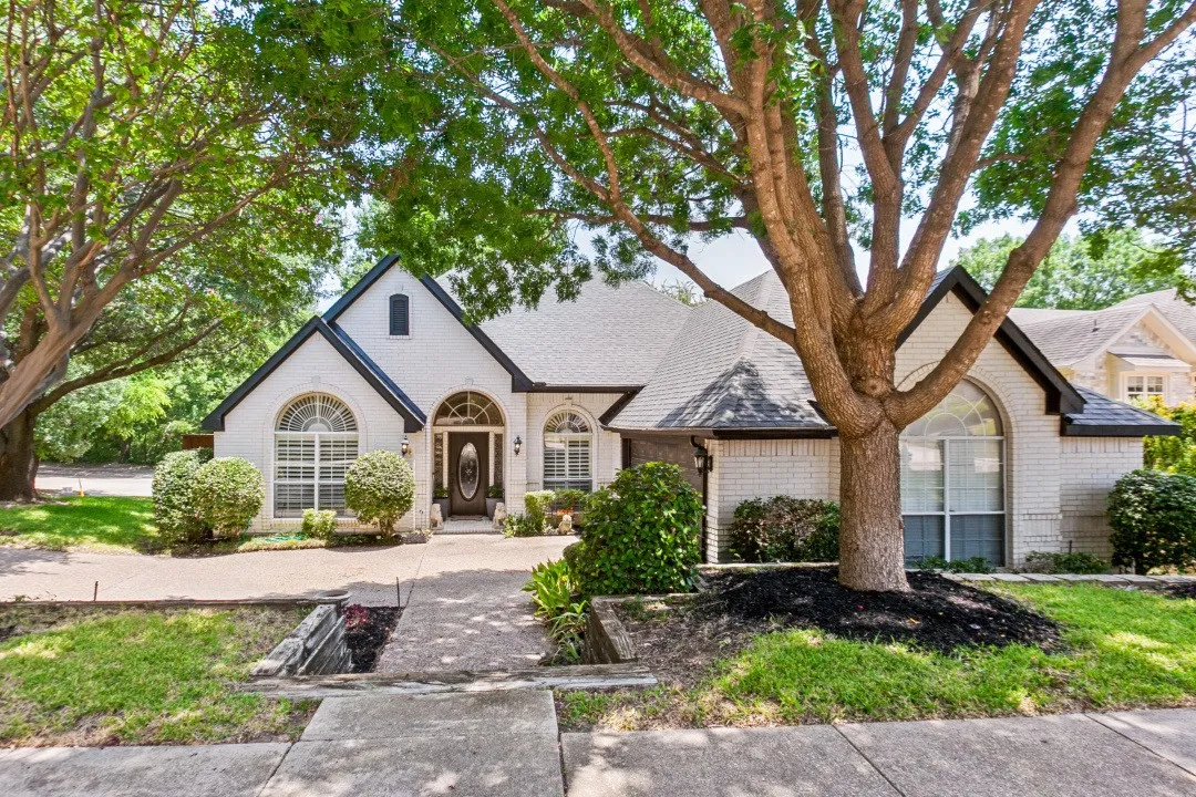 White brick exterior with black trim, arched windows, and a dark front entry door