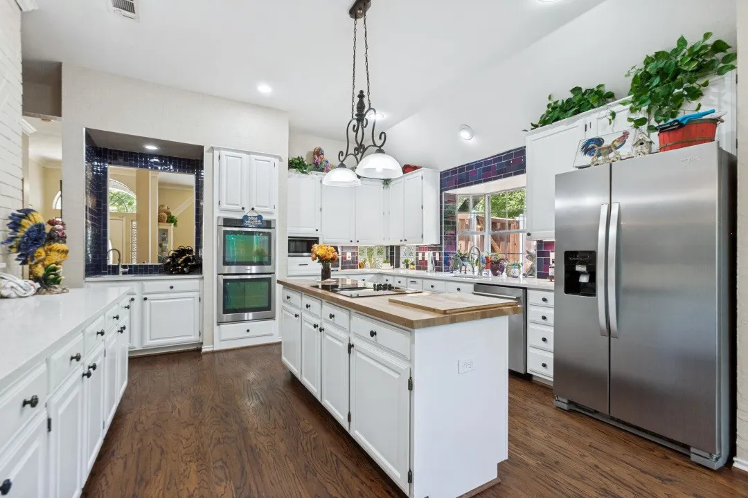 Kitchen featuring white cabinetry, stainless steel appliances, wood-finish flooring, and a central island with a butcher block countertop