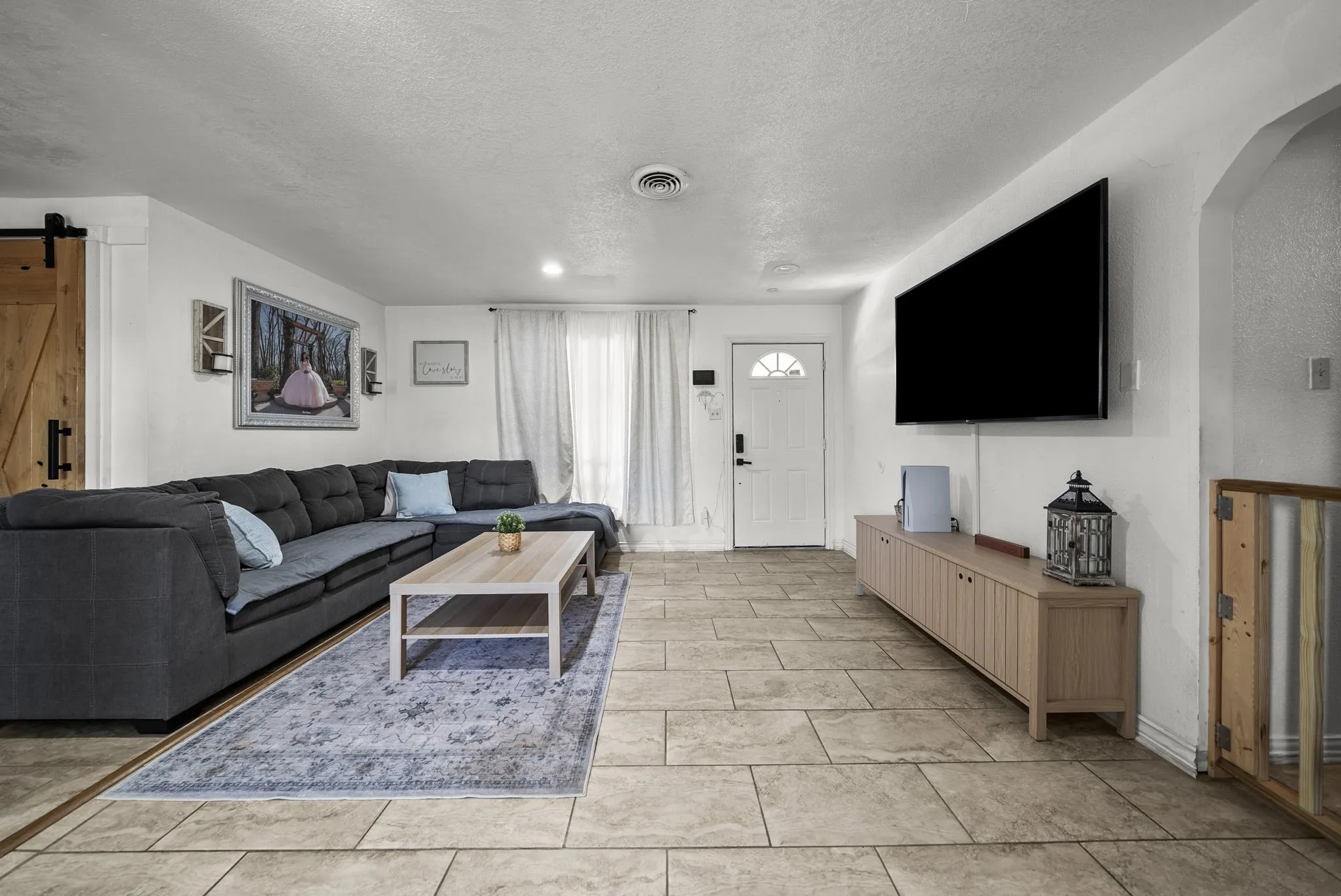 Tiled flooring, white entry door with arched glass, recessed lighting, and a barn-style sliding door