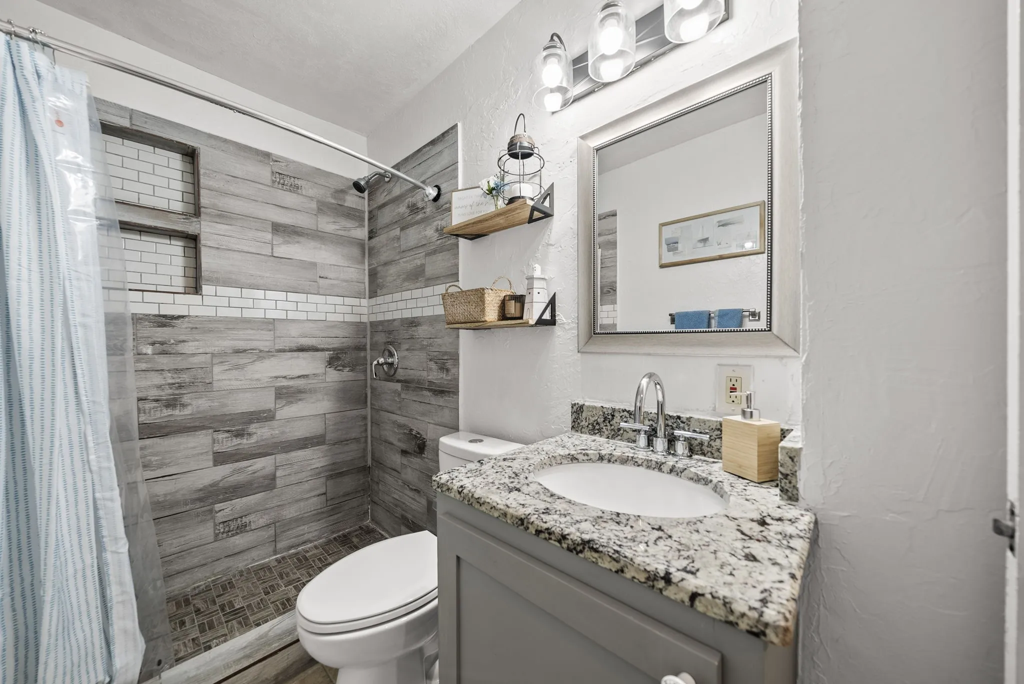 Shower with wood-look tile surround and subway tile accents, featuring recessed shelving