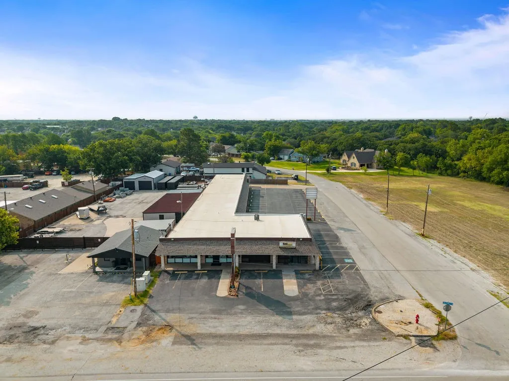 Expansive commercial property featuring a main building with an L-shaped footprint, multiple outbuildings, and a large paved lot