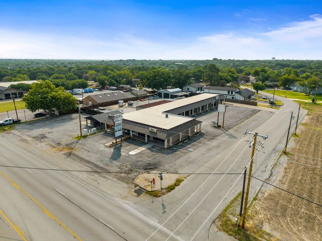 Commercial property featuring a large asphalt parking area, multiple buildings, and direct road frontage