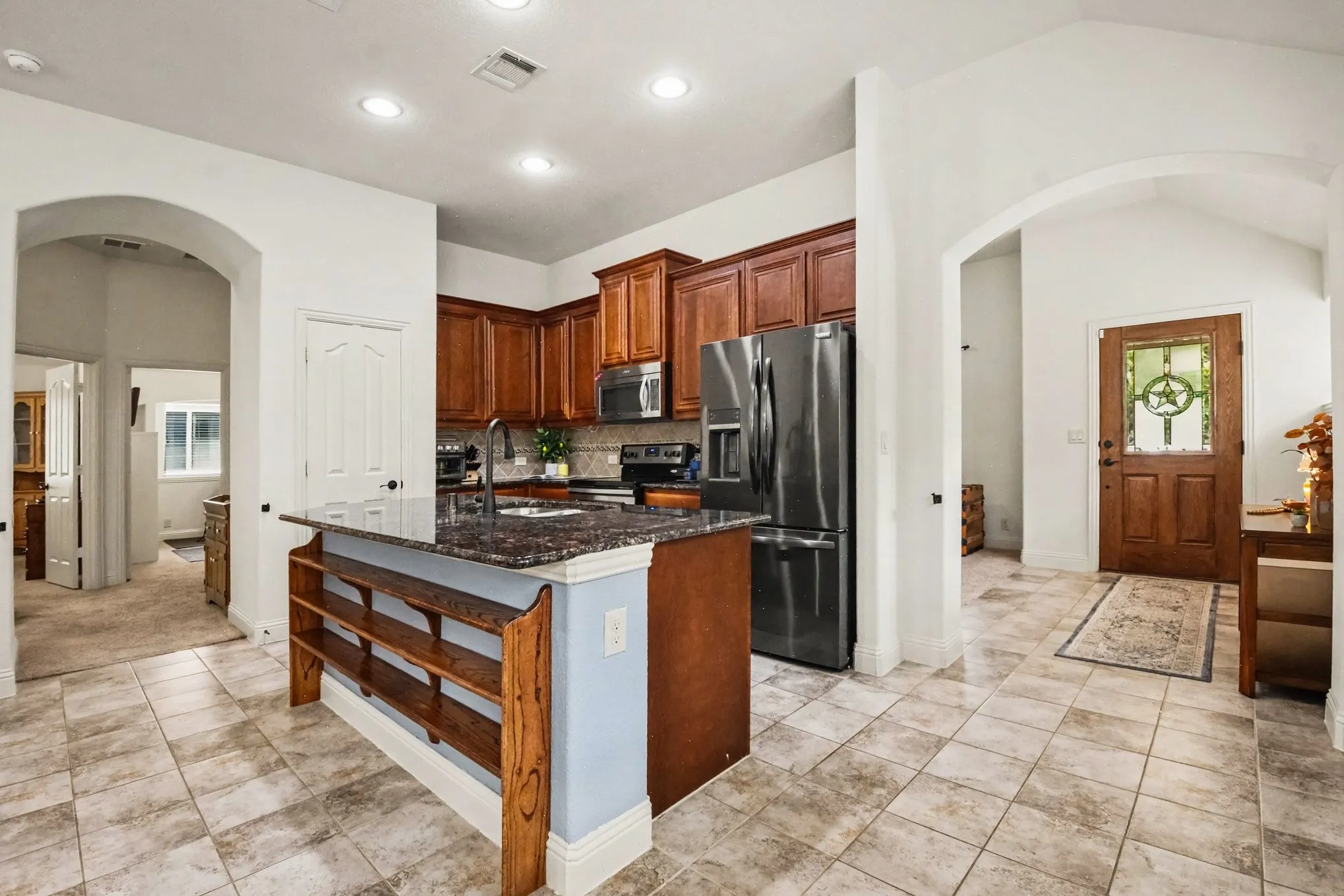 Kitchen featuring wood cabinetry, dark stone countertops, and stainless steel appliances