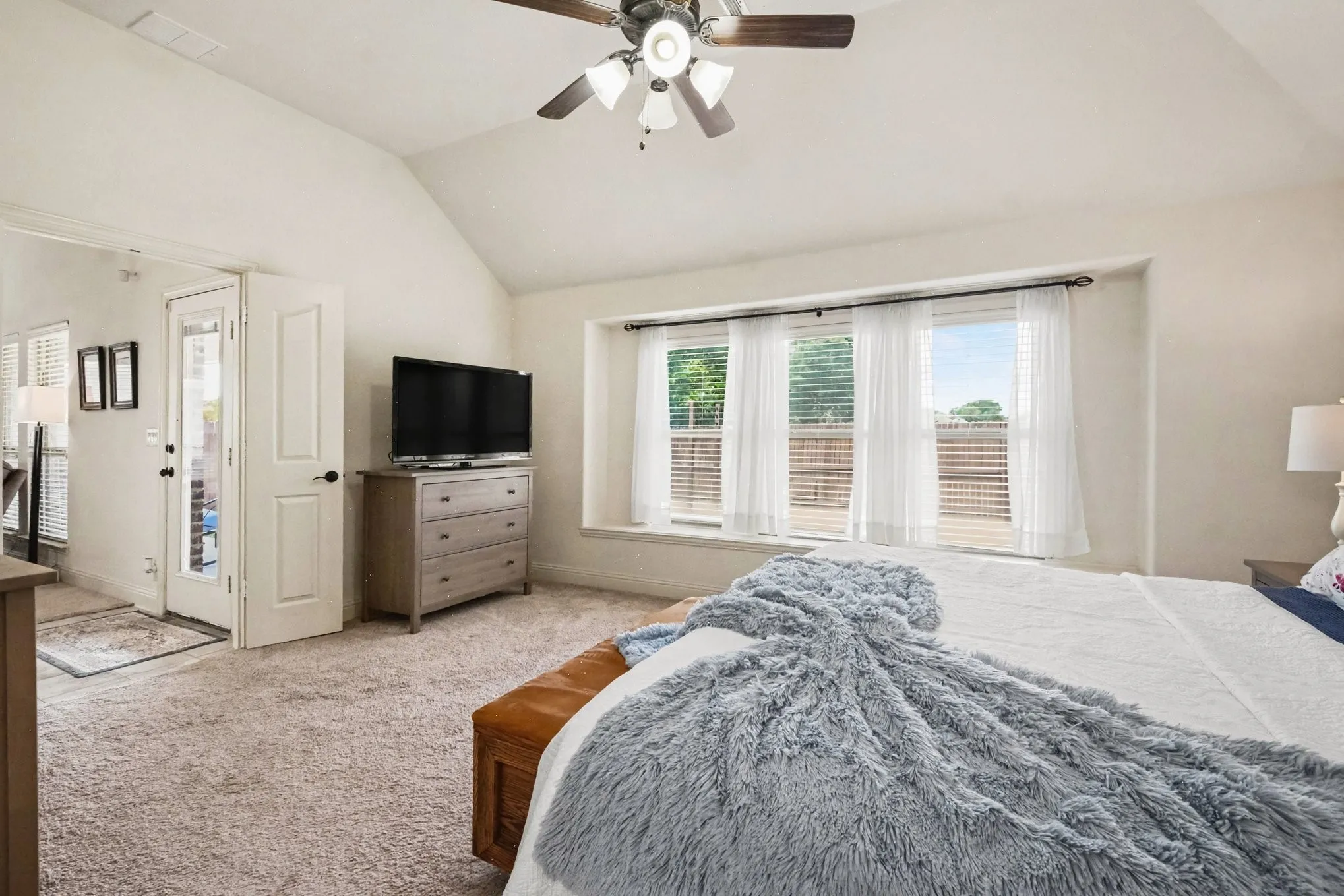 Angled ceiling with a ceiling fan, carpeted flooring, and a bay window