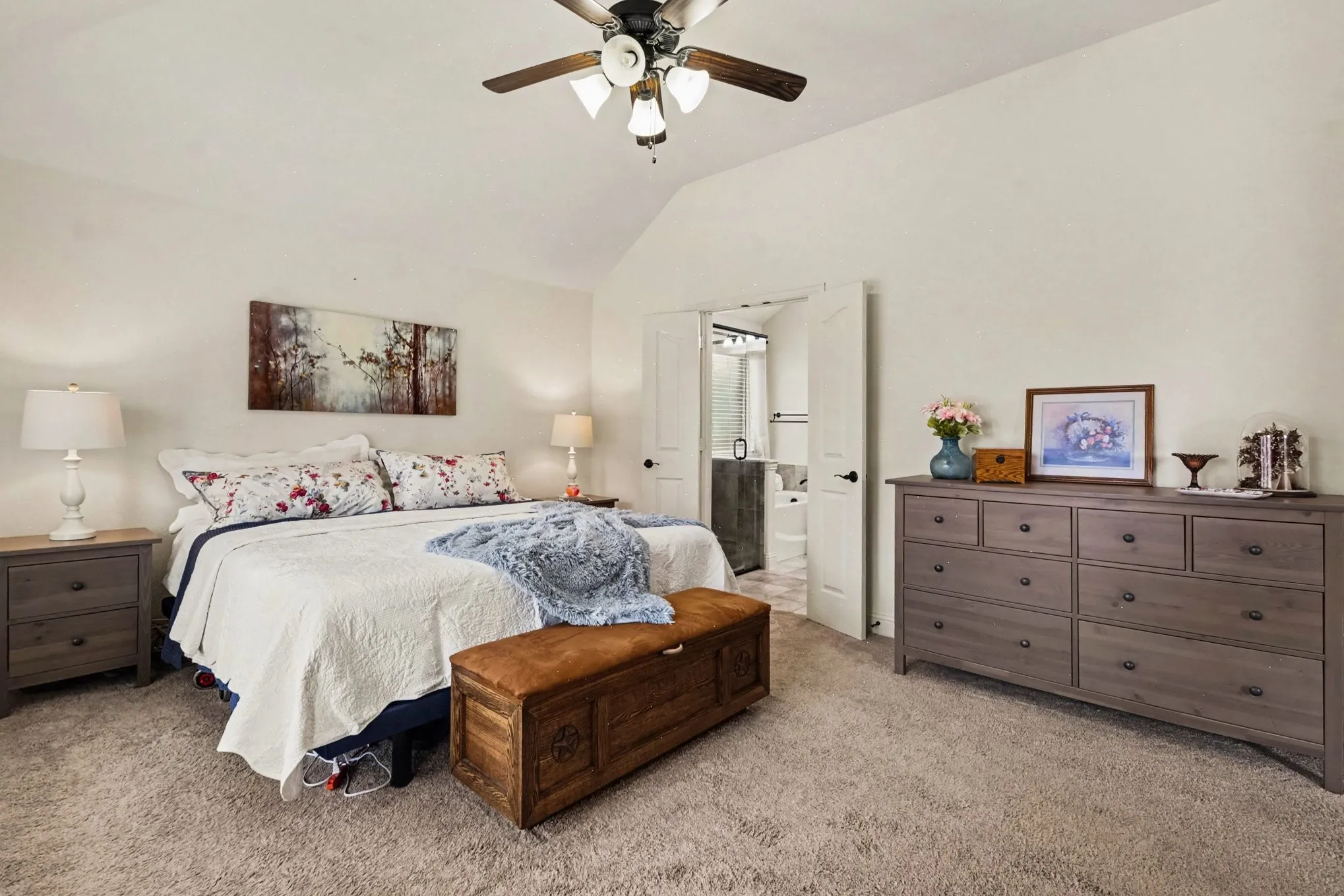 Vaulted ceiling with a ceiling fan, carpeted flooring, and double doors opening to an adjoining room