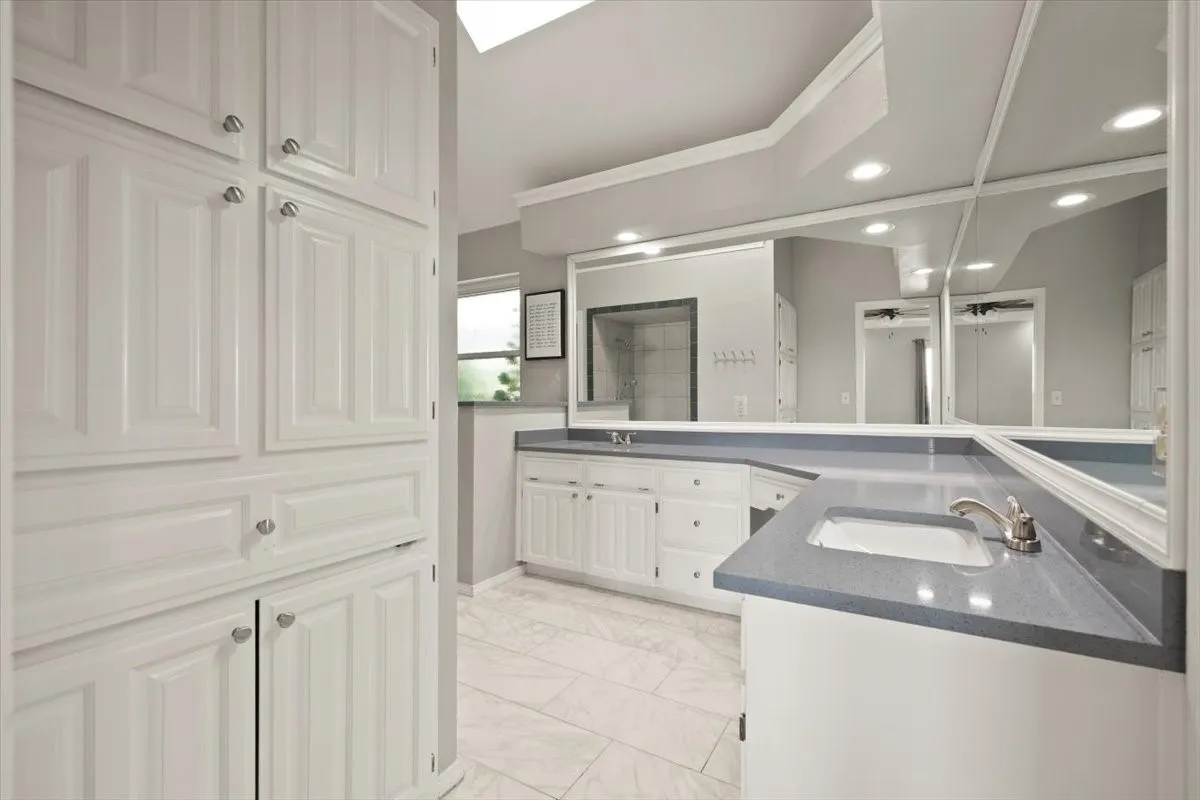 Extensive built-in cabinetry, dual vanities with integrated sinks, and light-toned tile flooring