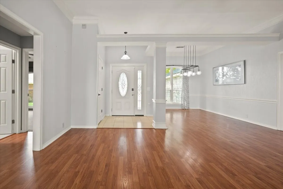Spacious interior featuring wood-finish flooring, an ornate front entry door, and a modern chandelier