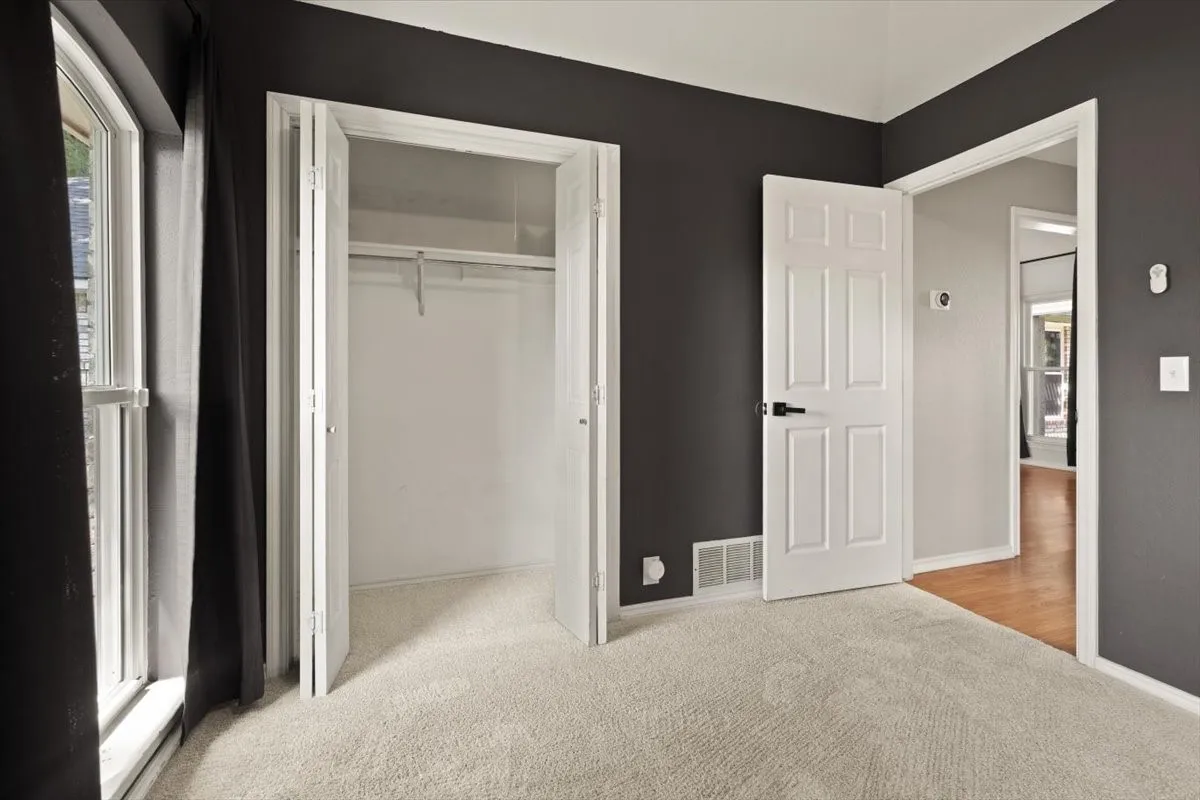 Plush carpet flooring, white trim details, bi-fold closet doors, and a paneled interior door with dark hardware