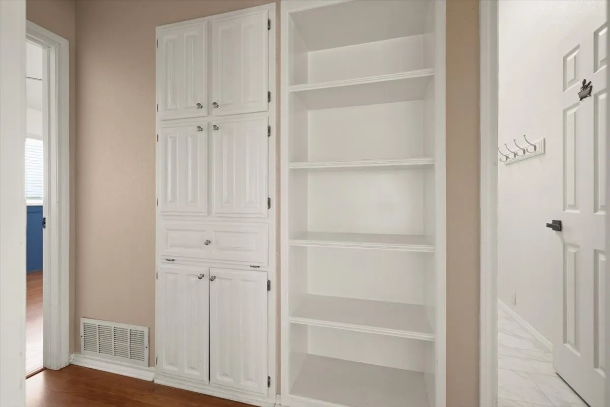 Built-in cabinetry with paneled doors, white painted finish, and metal hardware