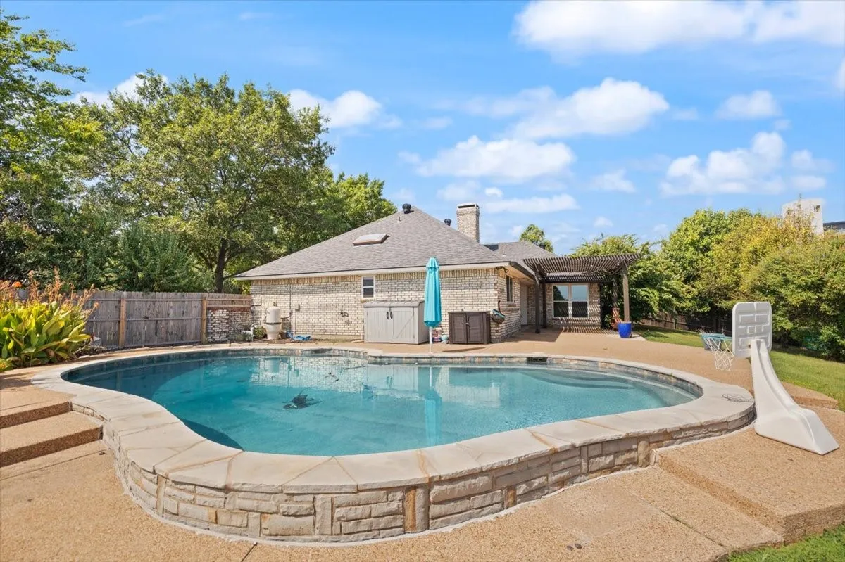 Outdoor pool with stone coping and integrated steps, surrounded by a textured concrete deck