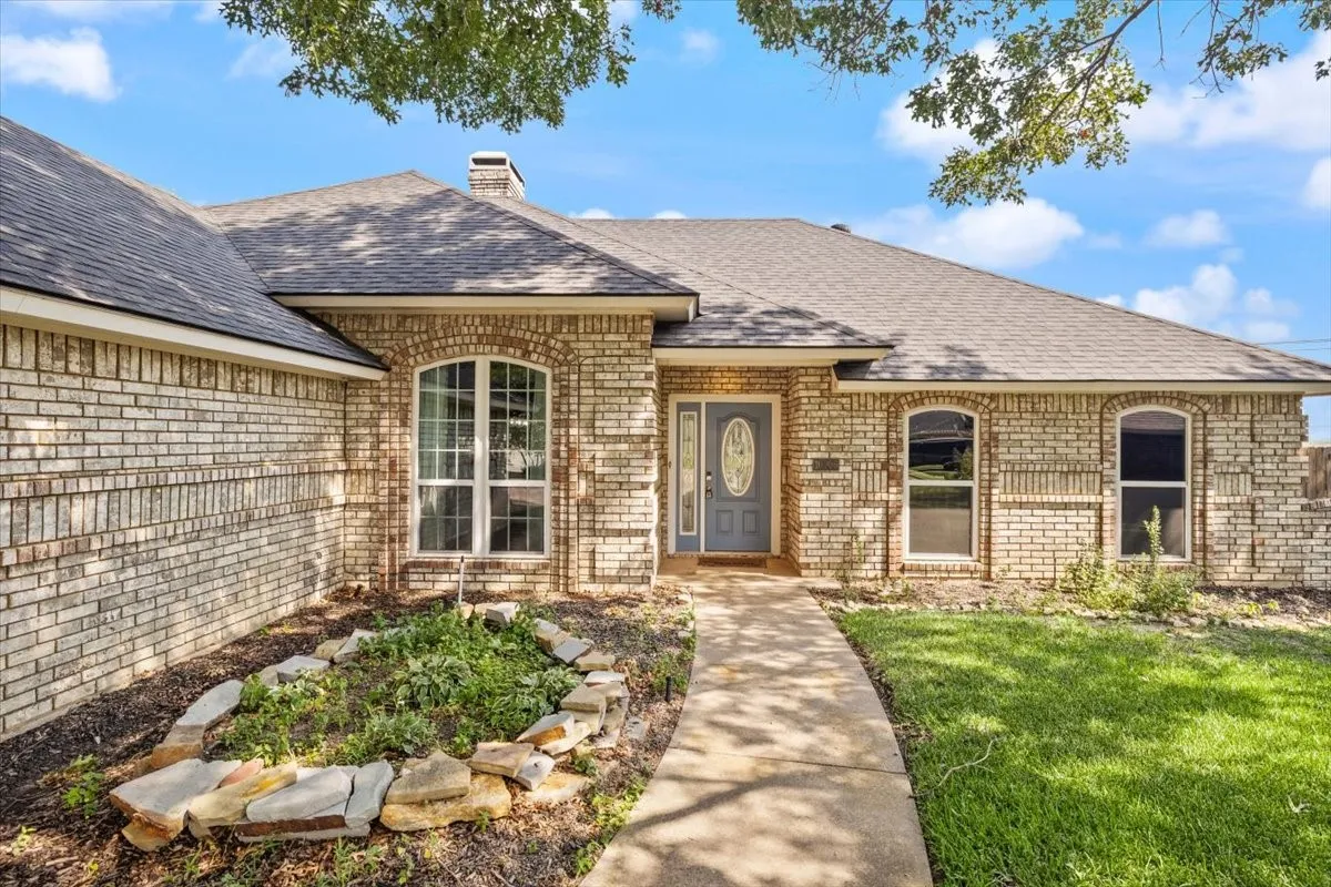 Welcoming brick exterior with arched entryway, complemented by mature landscaping and manicured lawn
