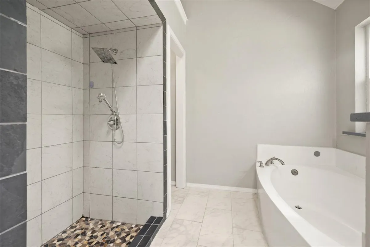 Walk-in shower with a rain showerhead, handheld shower, and pebble-tile flooring