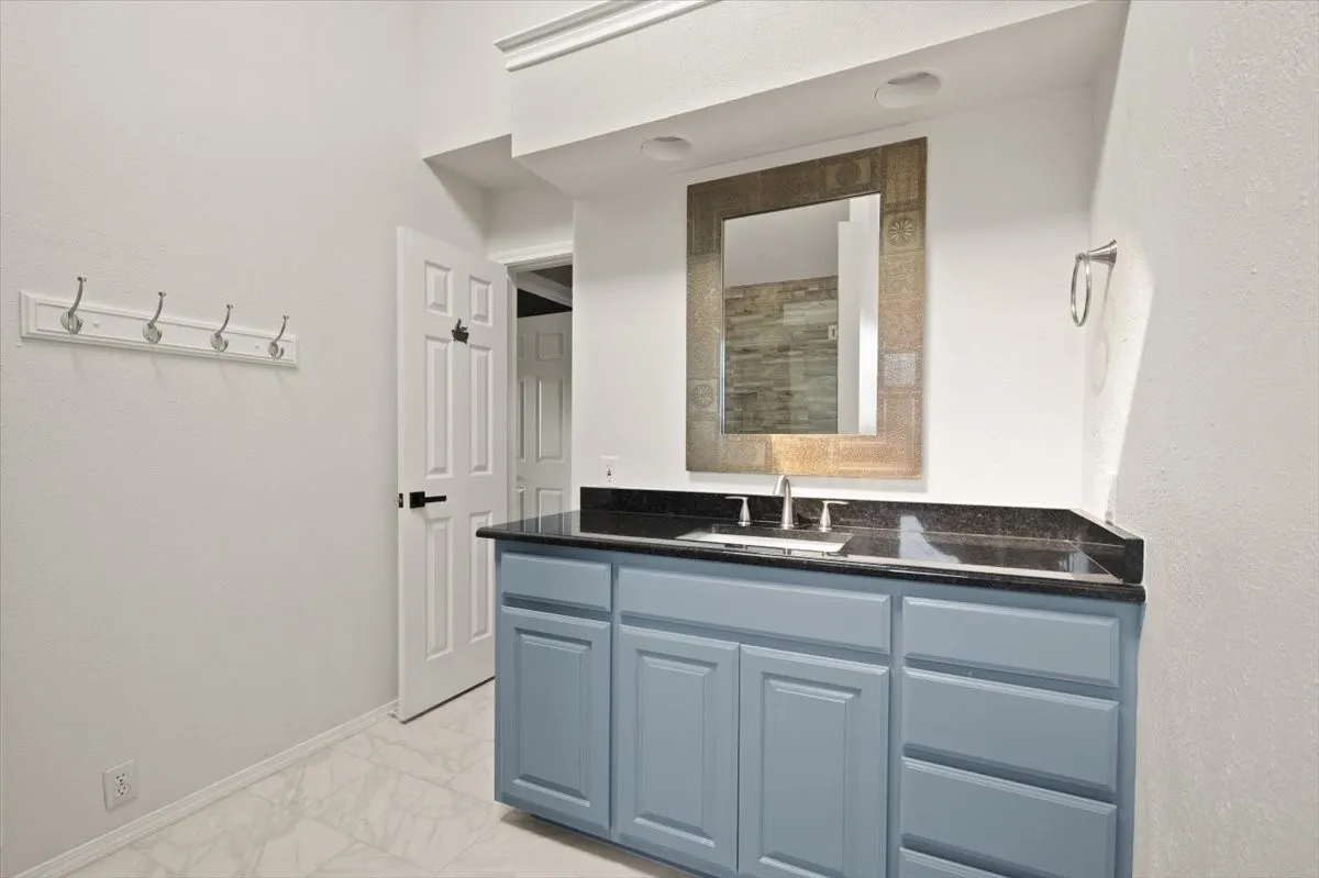 Vanity with blue cabinetry, dark countertop, and integrated sink