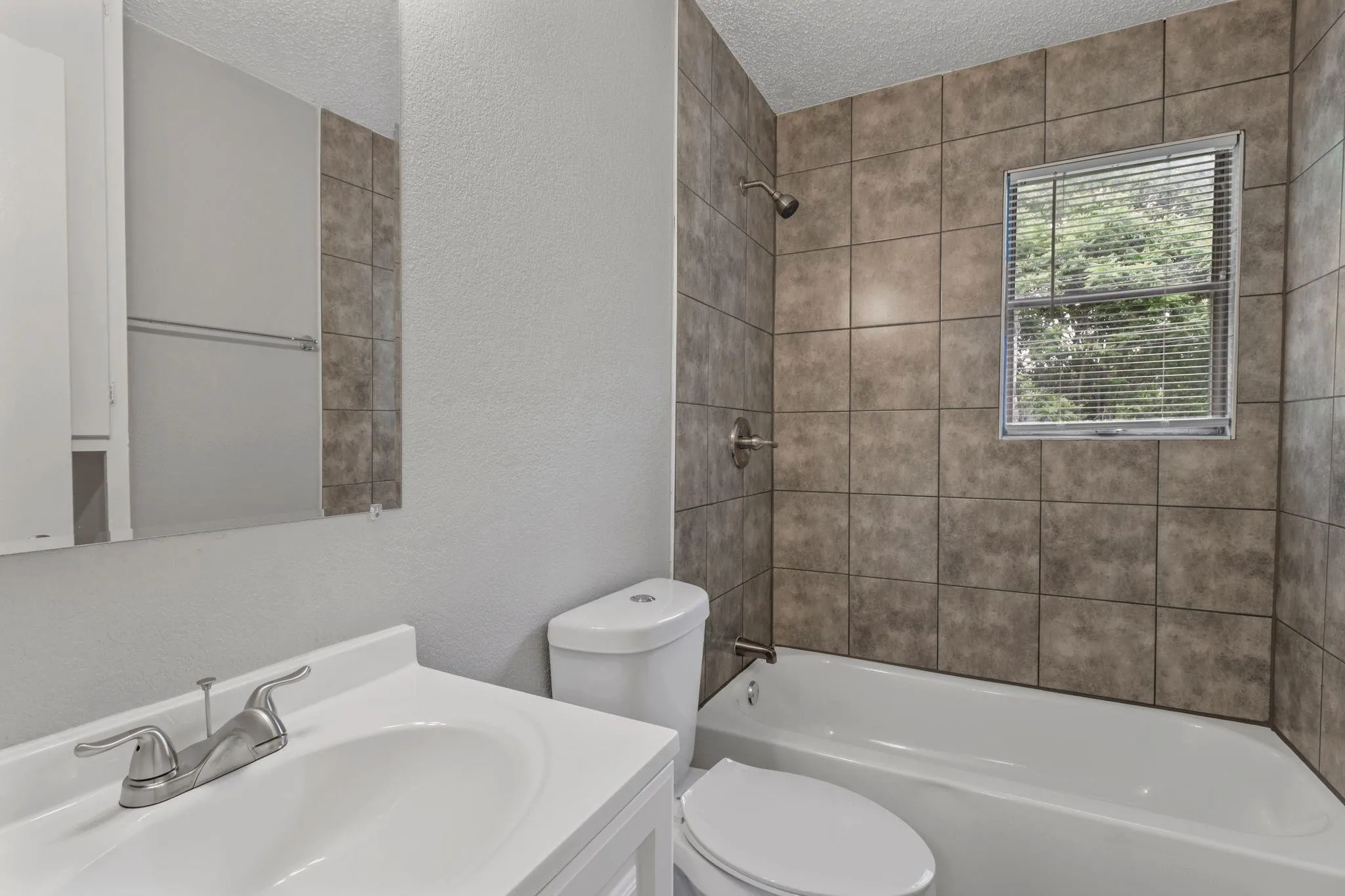 Bathroom featuring a white vanity with integrated sink, chrome-finish faucet, and coordinating toilet