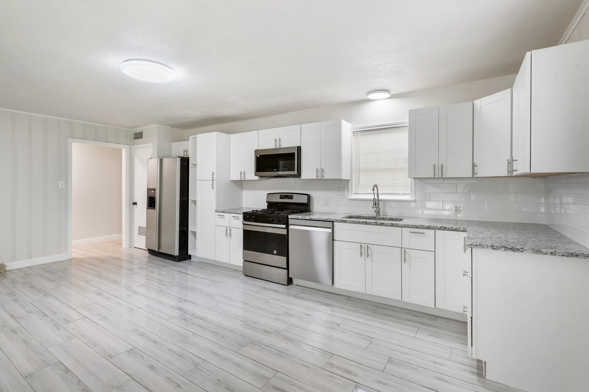 Updated kitchen featuring white shaker cabinetry, granite countertops, stainless steel appliances, and abundant cabinet space.