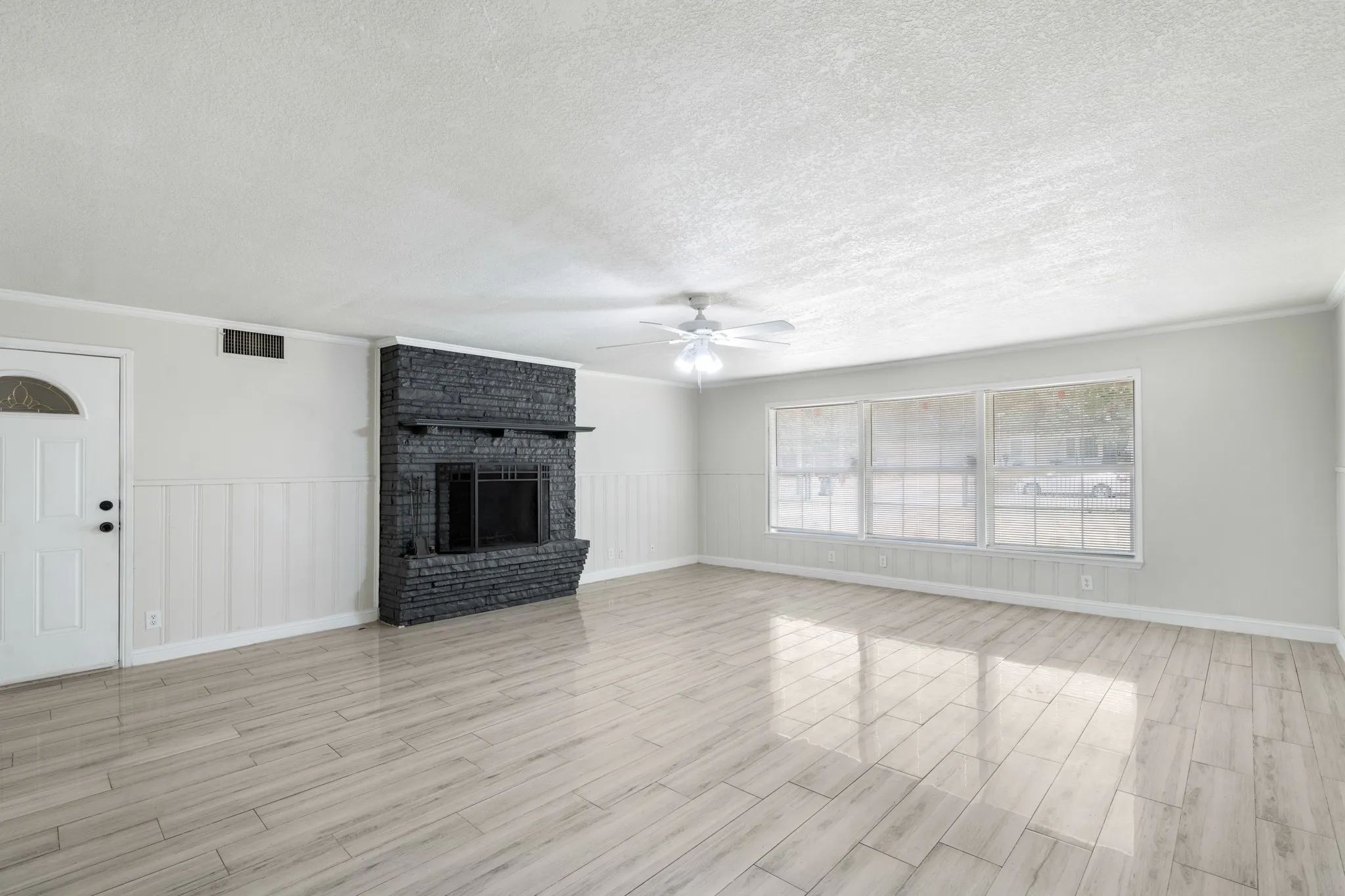 Spacious living room flooded with natural light from large windows that face the front yard.