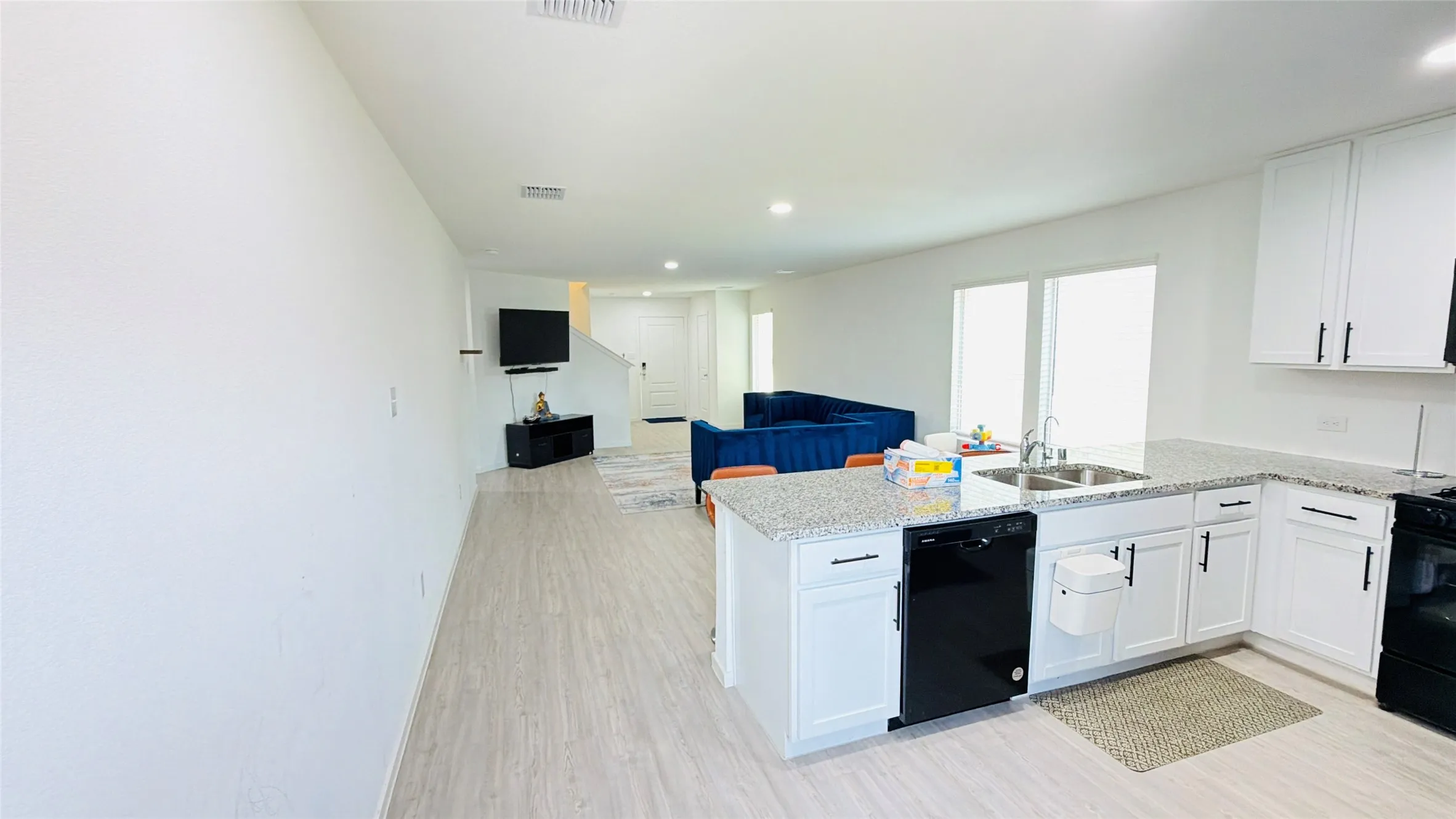 Open-concept layout with wood-finish flooring, white cabinetry, and light-colored countertops