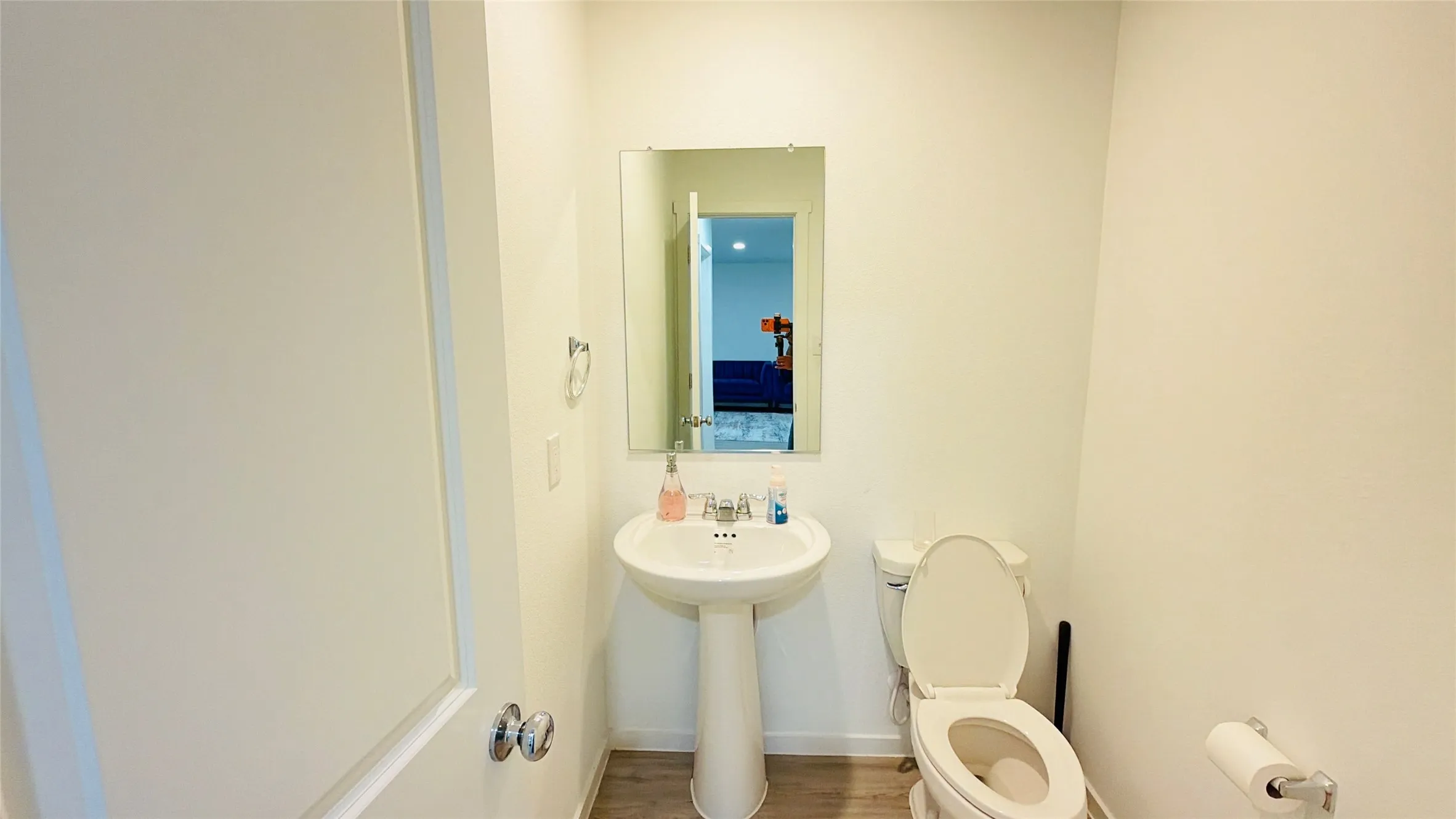 Pedestal sink, wall-mounted rectangular mirror, and wood-finish flooring