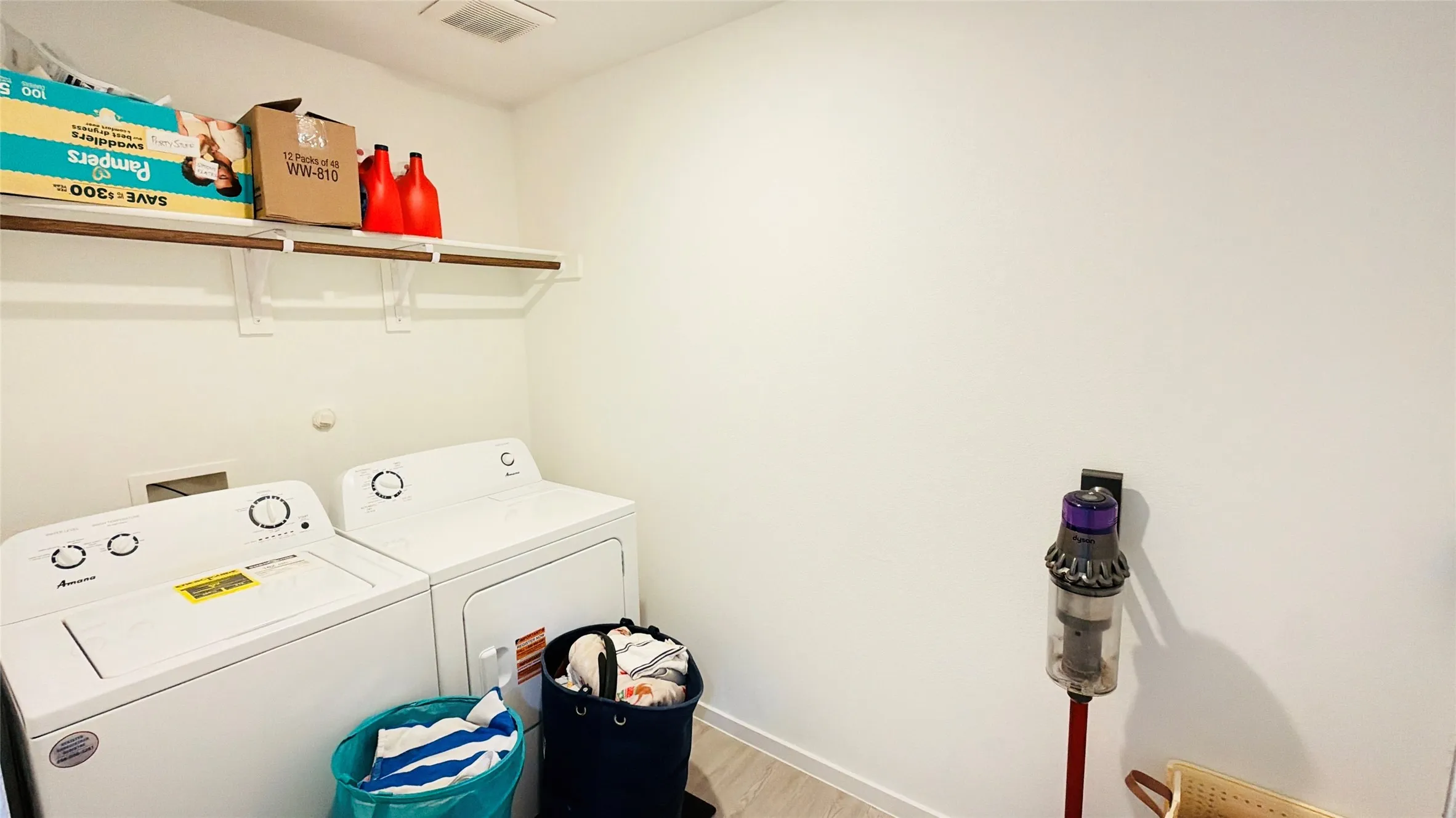 Laundry area featuring a top-load washing machine, front-load dryer, and wall-mounted shelving