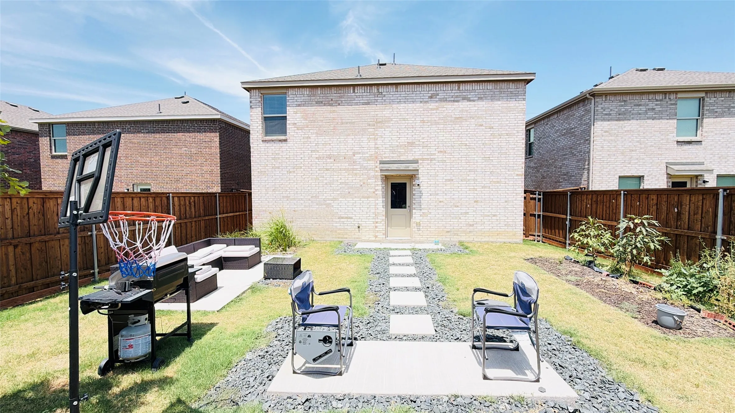 Expansive backyard featuring a manicured lawn, wood fencing, and a concrete paver pathway