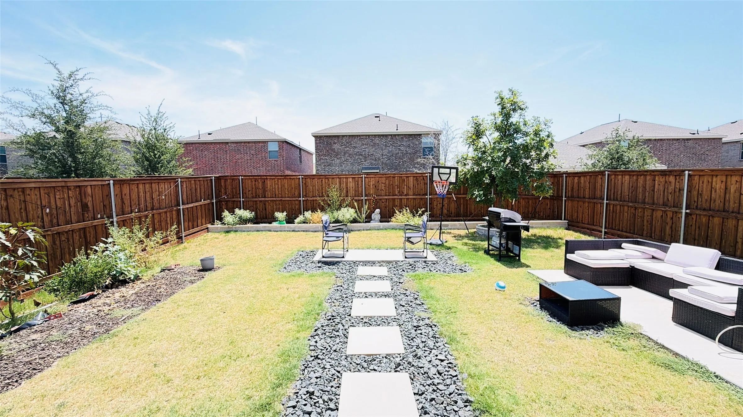 Expansive backyard featuring a privacy fence, concrete patio, and a paver pathway with gravel