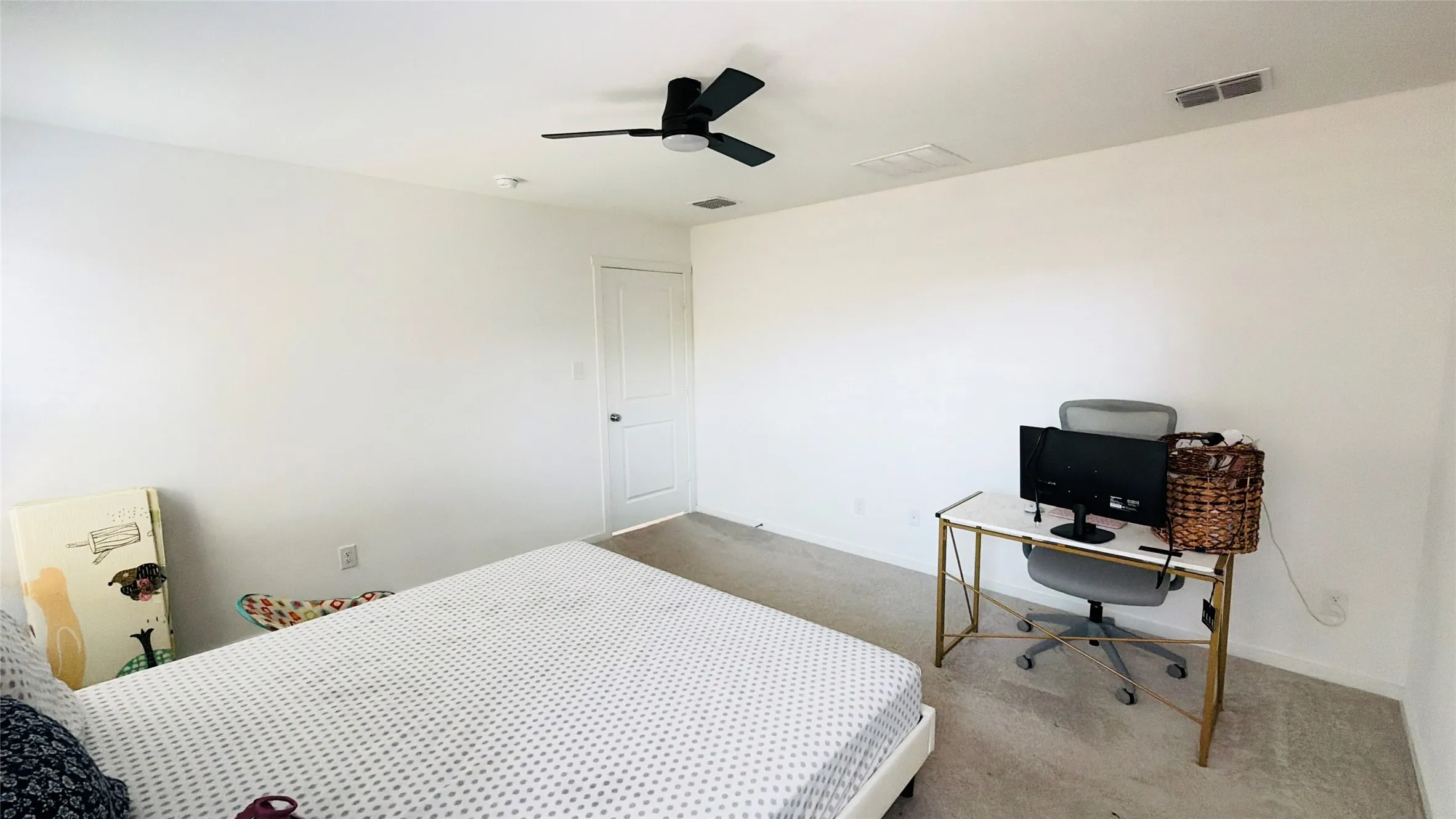 Light gray carpeted flooring, white painted walls, white two-panel interior door, and a ceiling-mounted fan with integrated lighting