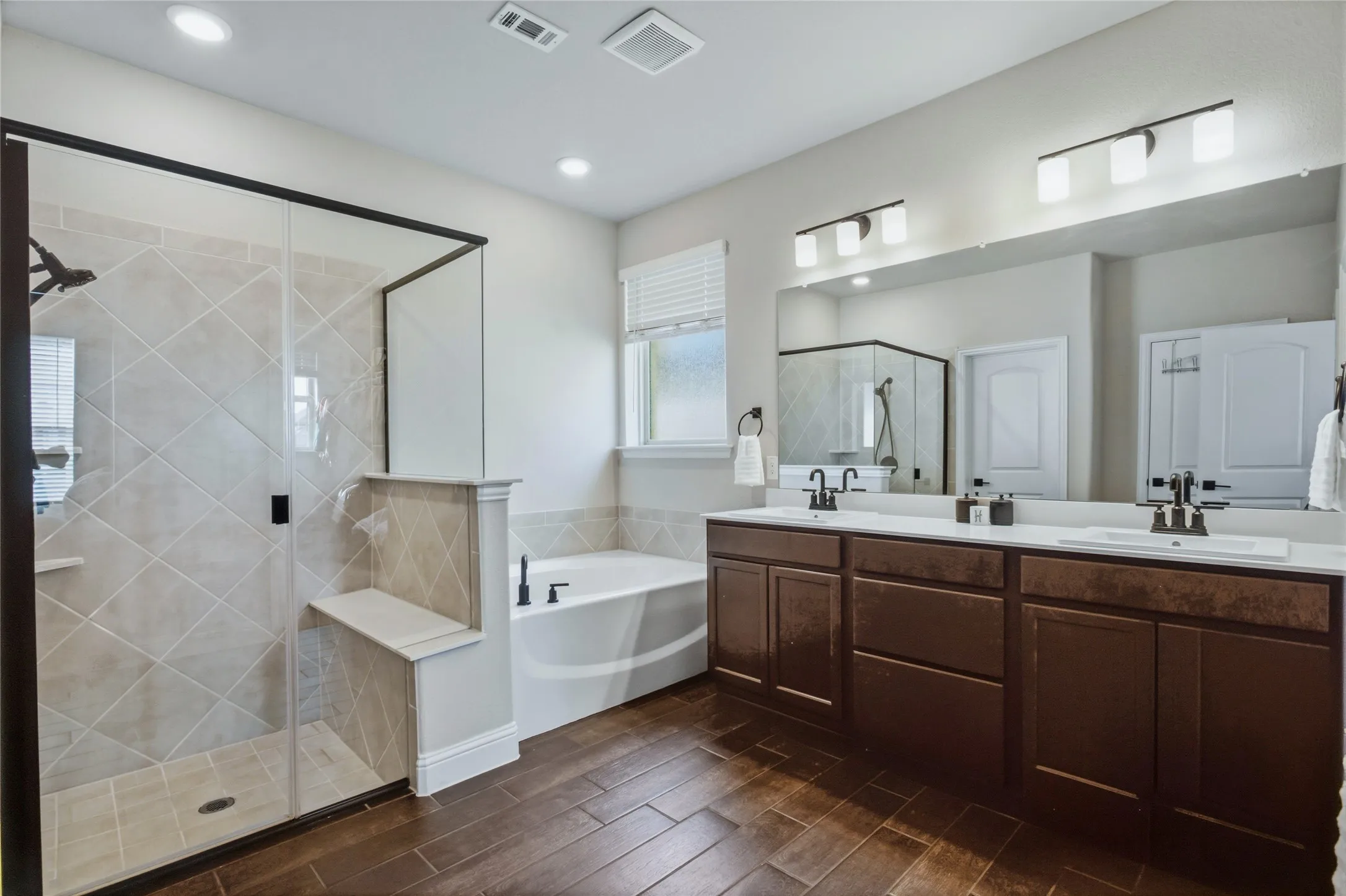 Well-appointed primary bath featuring dual vanities, soaking tub, separate shower, and ample natural light.