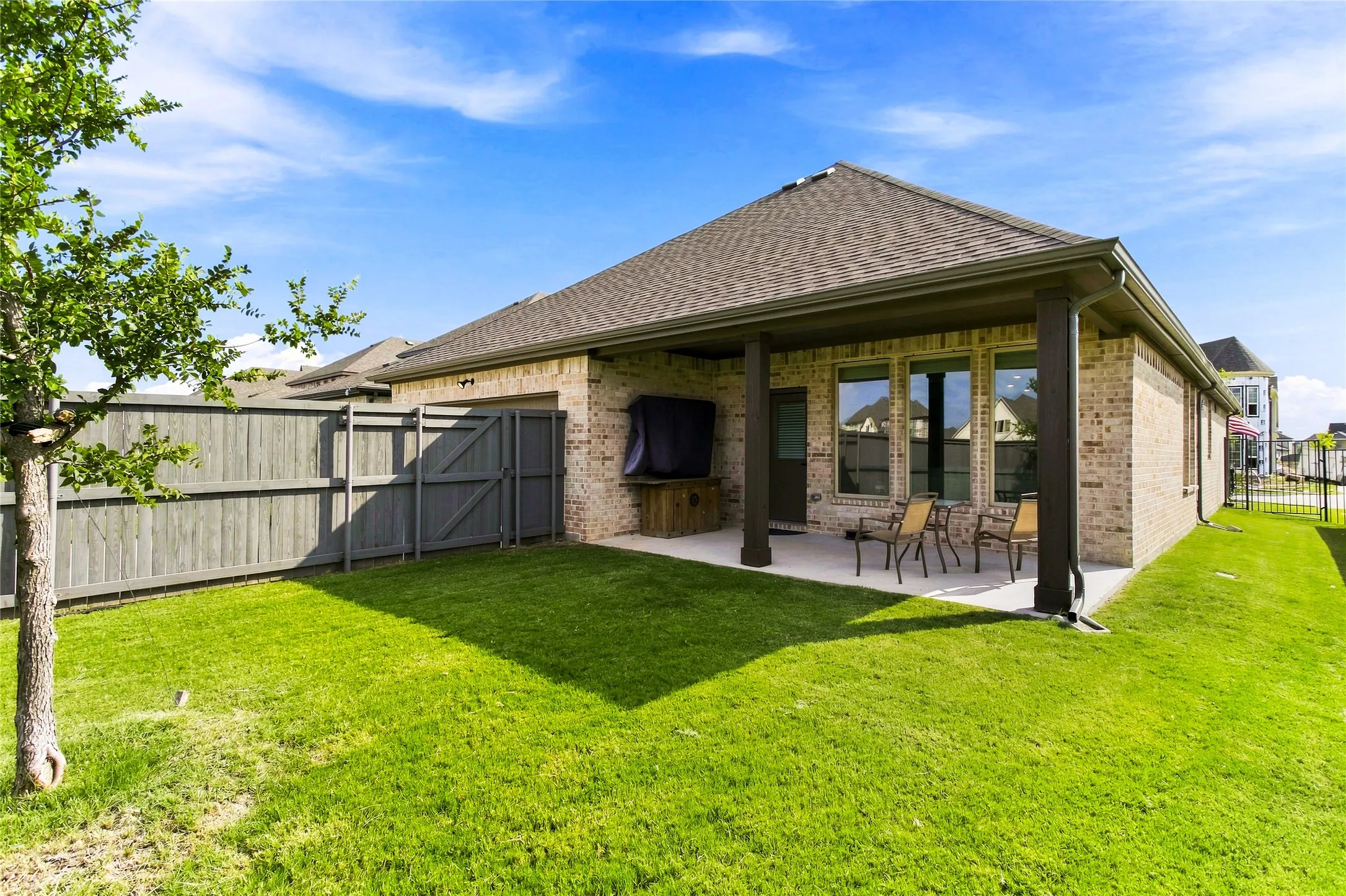Fenced backyard with a covered patio and open lawn space for outdoor enjoyment
