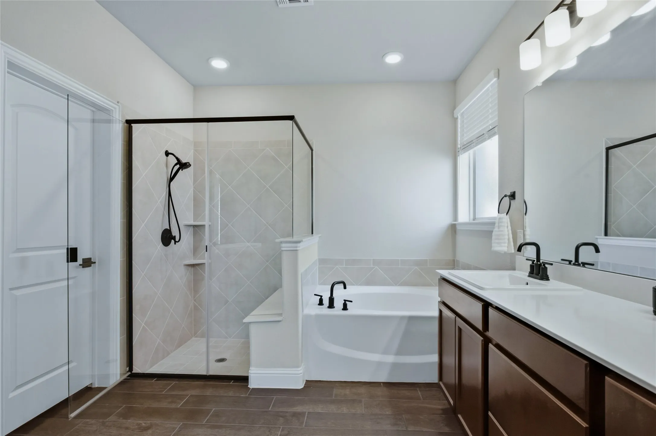 Bright and functional primary bathroom with generous vanity space and a separate shower and tub.