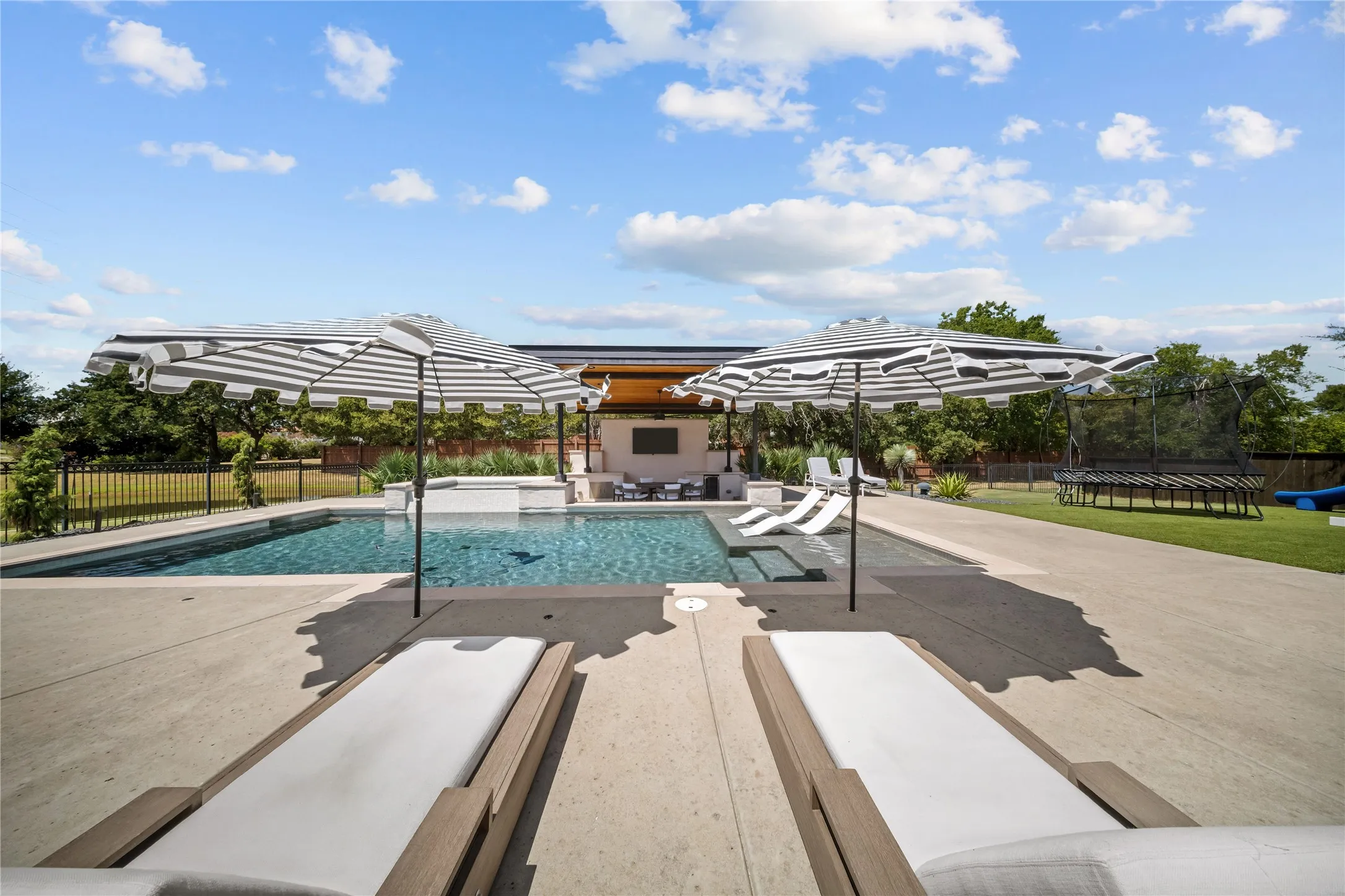 The ultimate entertainer's backyard resort with multiple sitting areas, backs to greenbelt walking trails, and a water view next to an accent pond.