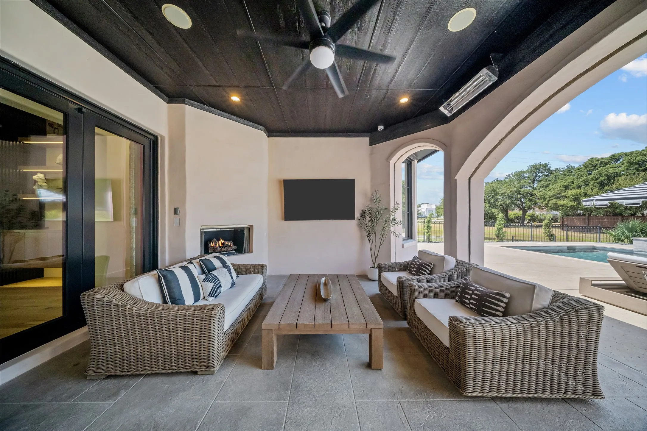 The covered outdoor patio sitting area has motorized screens and a wooded accent ceiling.