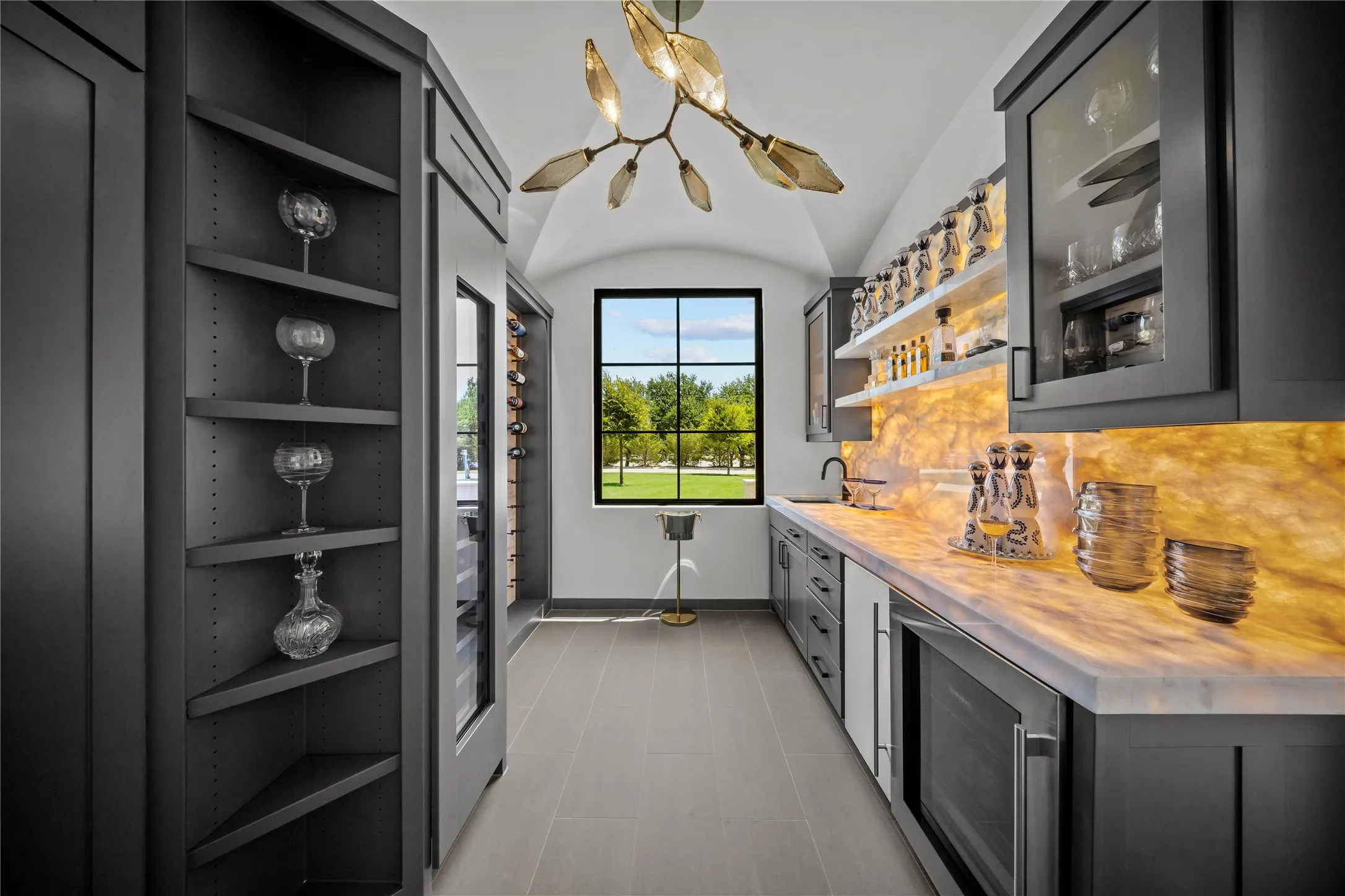 Cristalo backlit stone in wet bar and wine
room with icemaker, beverage refrigerator, wine cooler, and designer fixture.