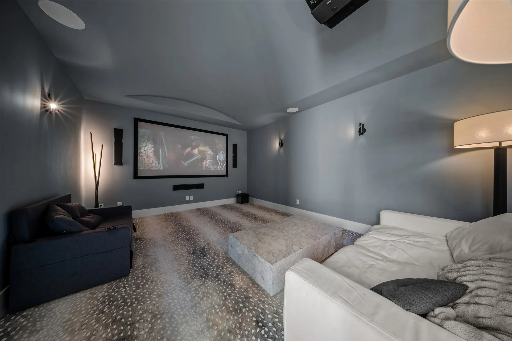 Downstairs media room with 4K projector, surround sound, plush carpeting, and accent lighting.