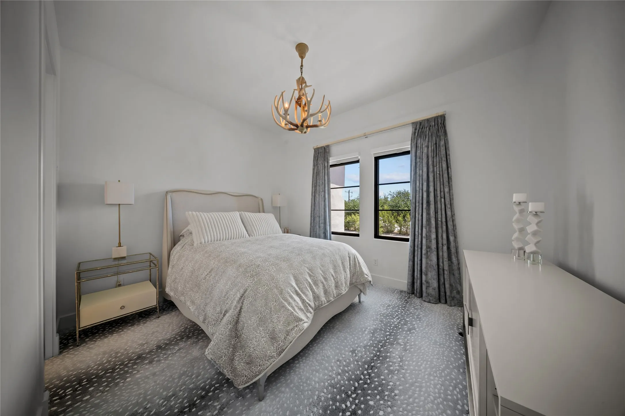 Upstairs secondary bedroom with high ceiling, custom lighting, ensuite bath, and window treatments.
