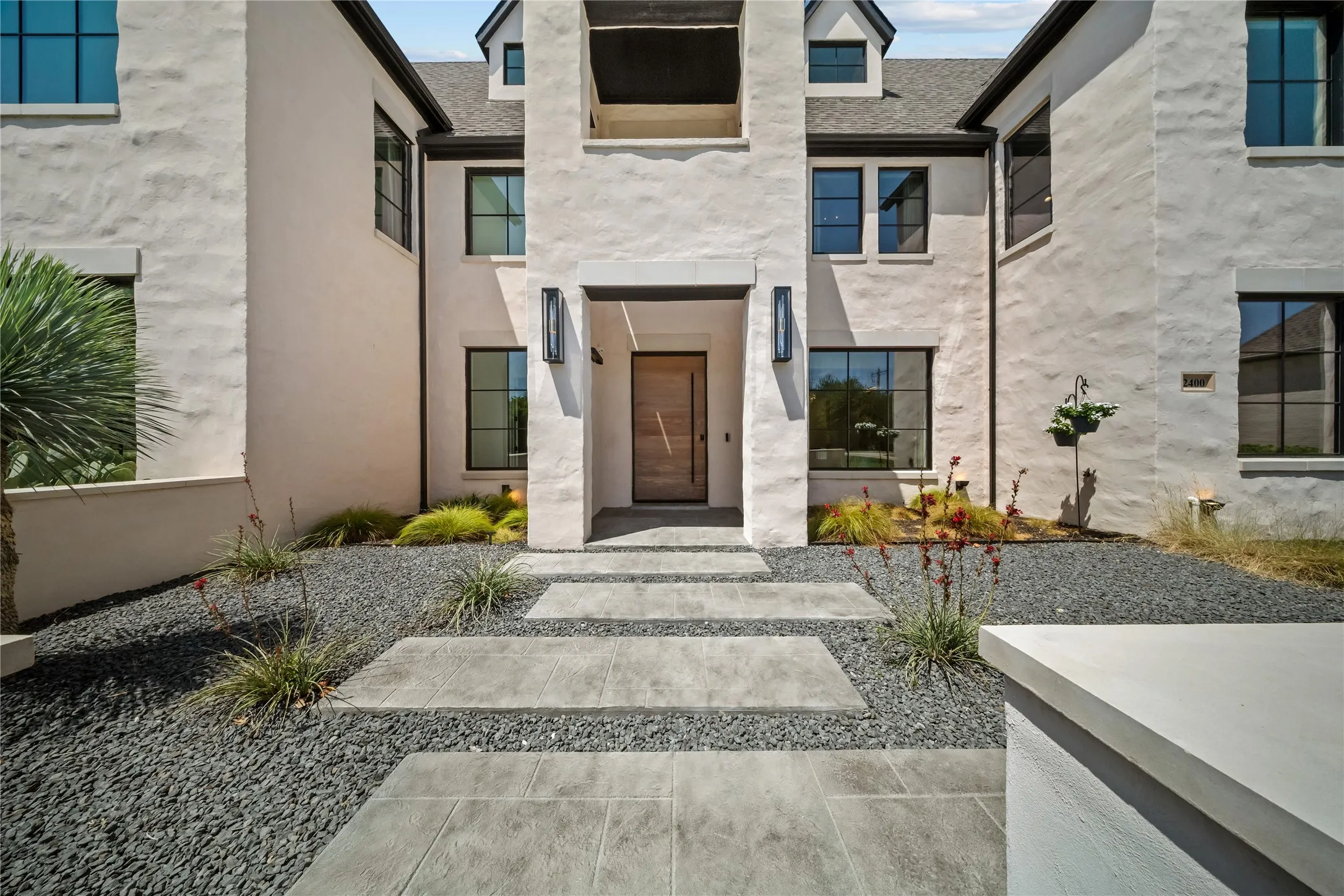 New hardscape installed on exterior grounds with custom stone accents and pivot door.