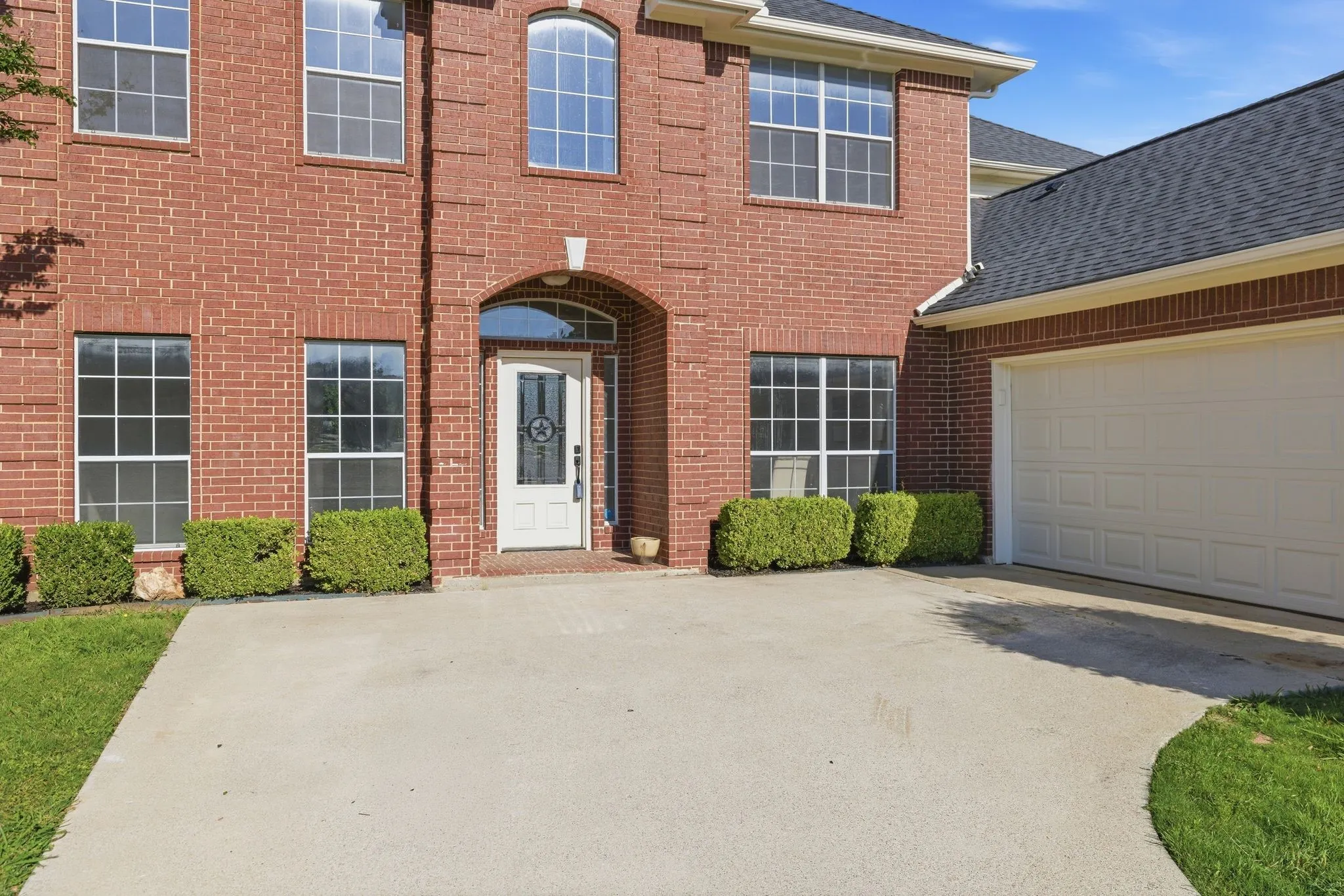 Brick exterior featuring a two-story design with arched entry, multi-pane windows, and an attached garage