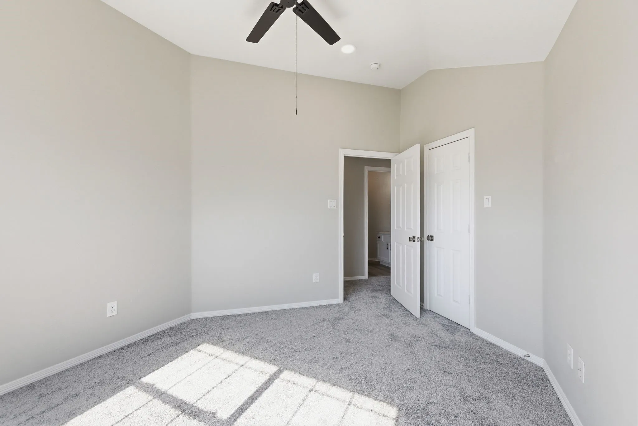 Carpeted room featuring light gray walls, a black ceiling fan, and a recessed light fixture