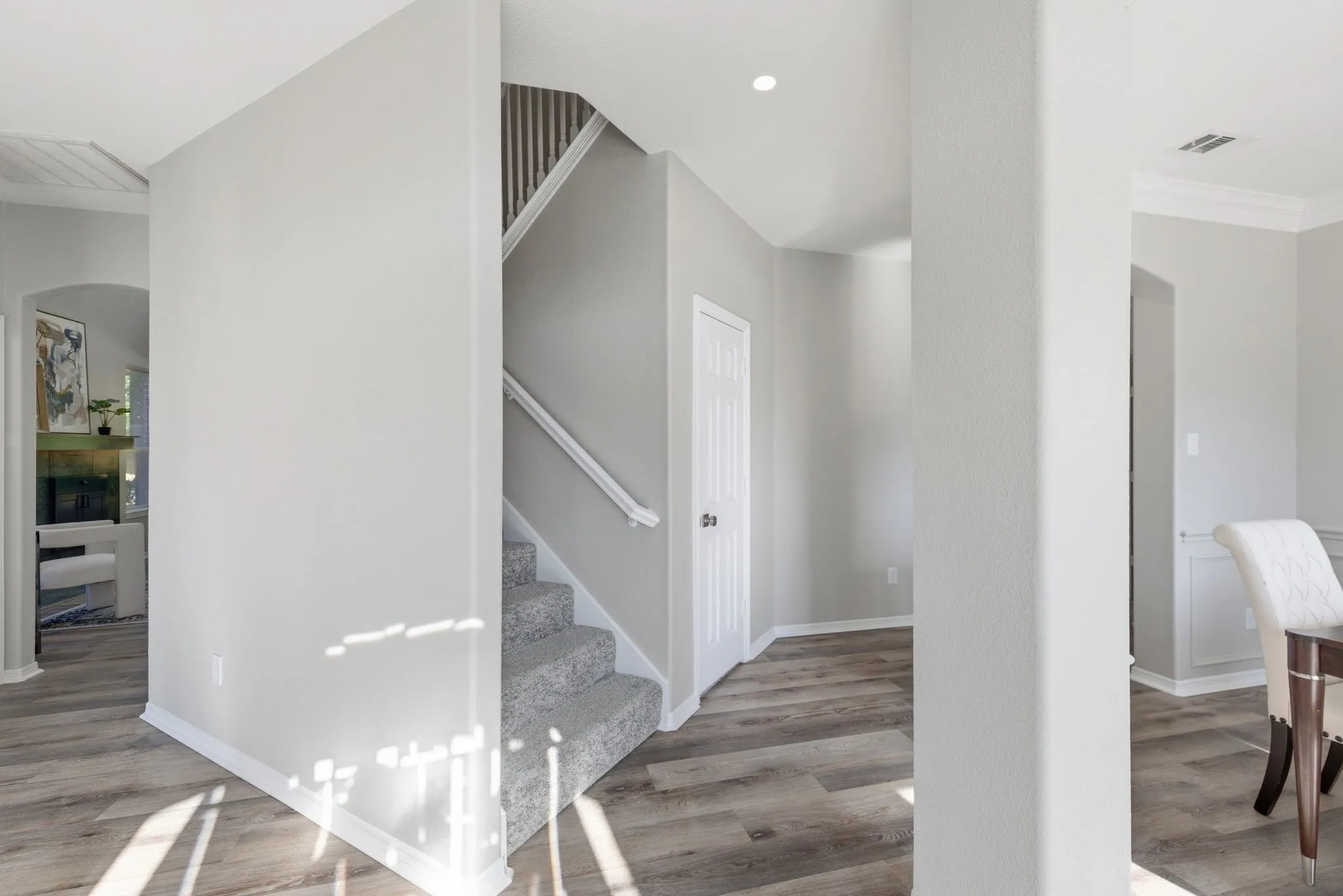 Interior entryway featuring wood-finish flooring and a carpeted staircase with a white handrail
